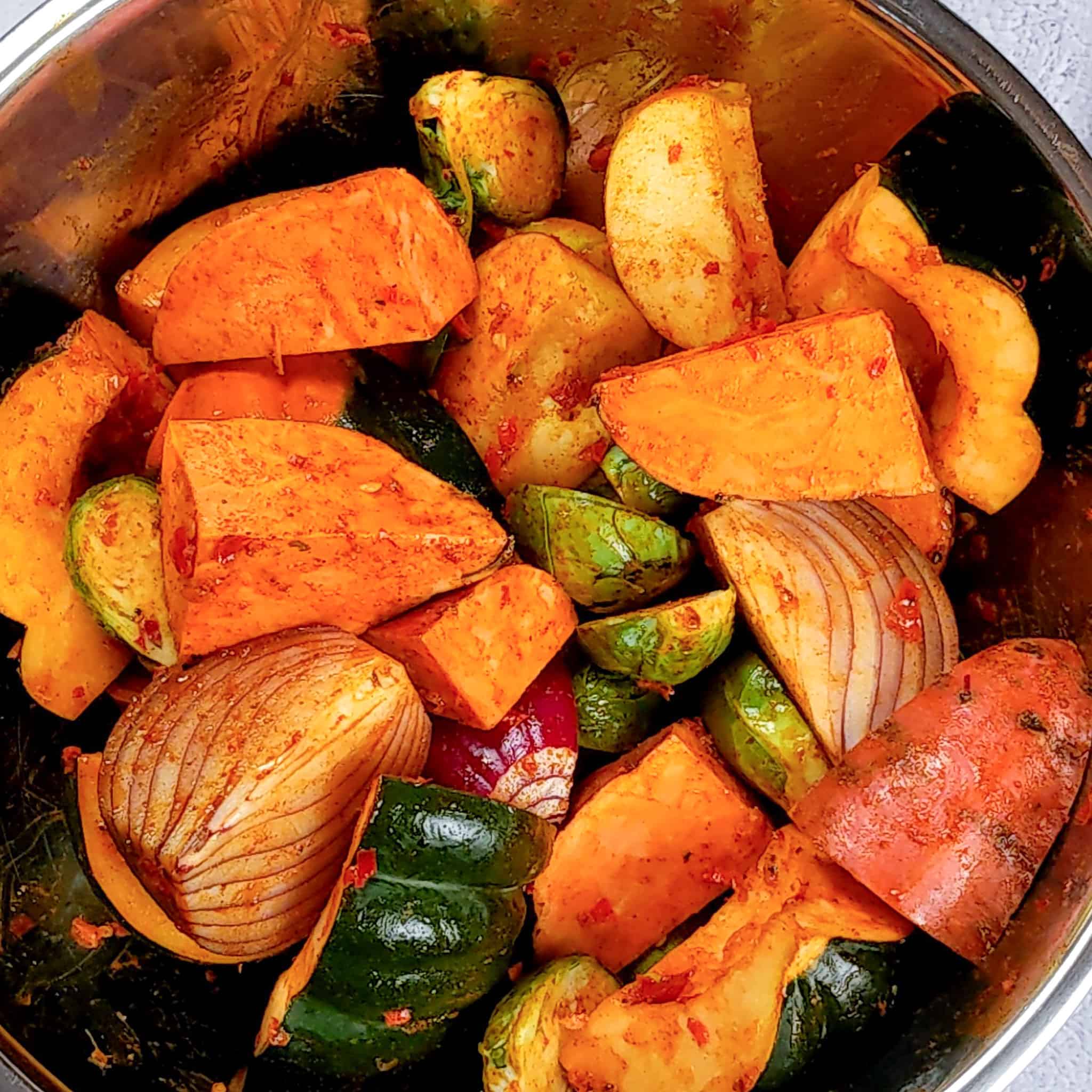 acorn squash, sweet potatoes, red onions, brussel sprouts, and apples cut into large chunks and tossed in seasoning in a large metal mixing bowl