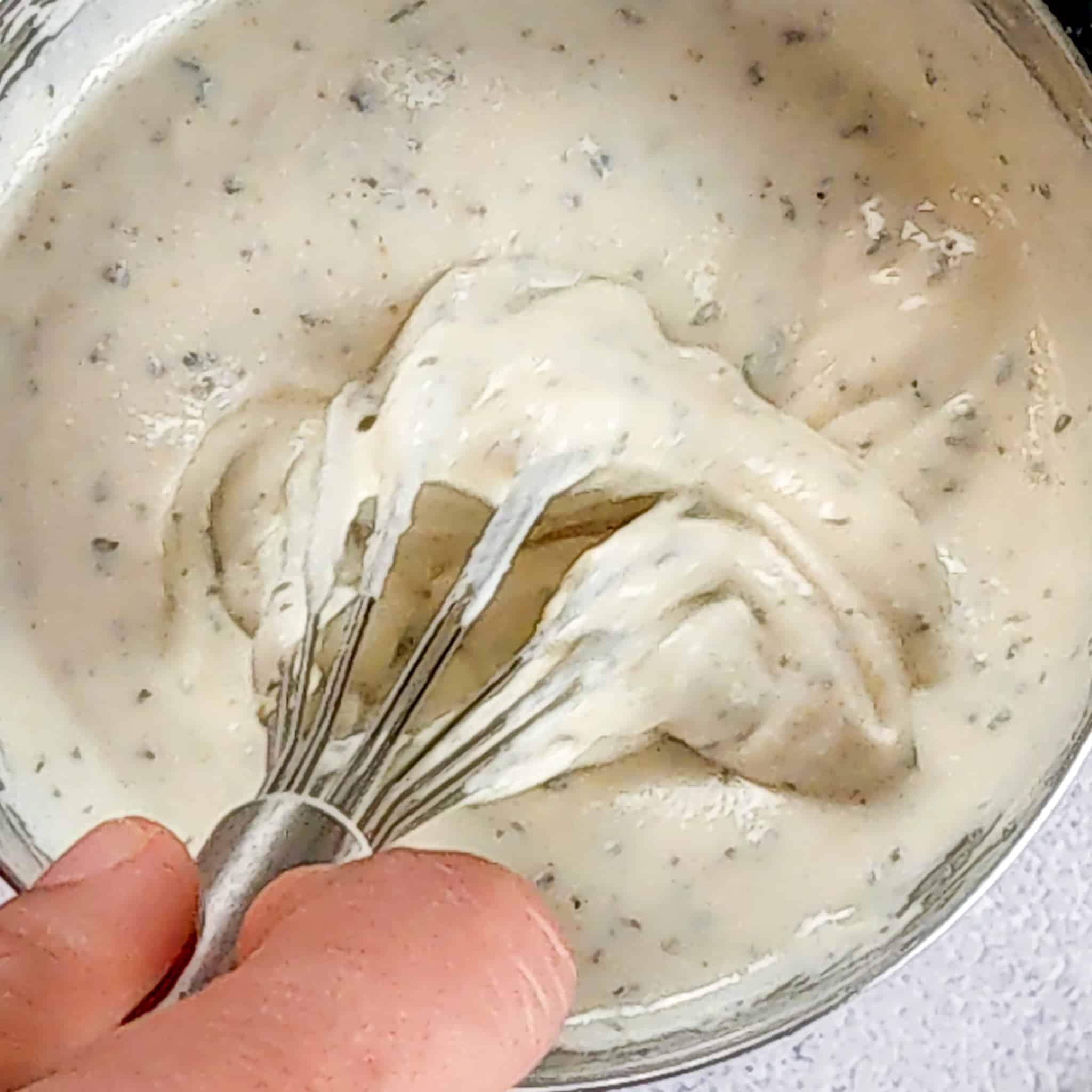 close up of the greek yogurt sauce being mixed with a whisk