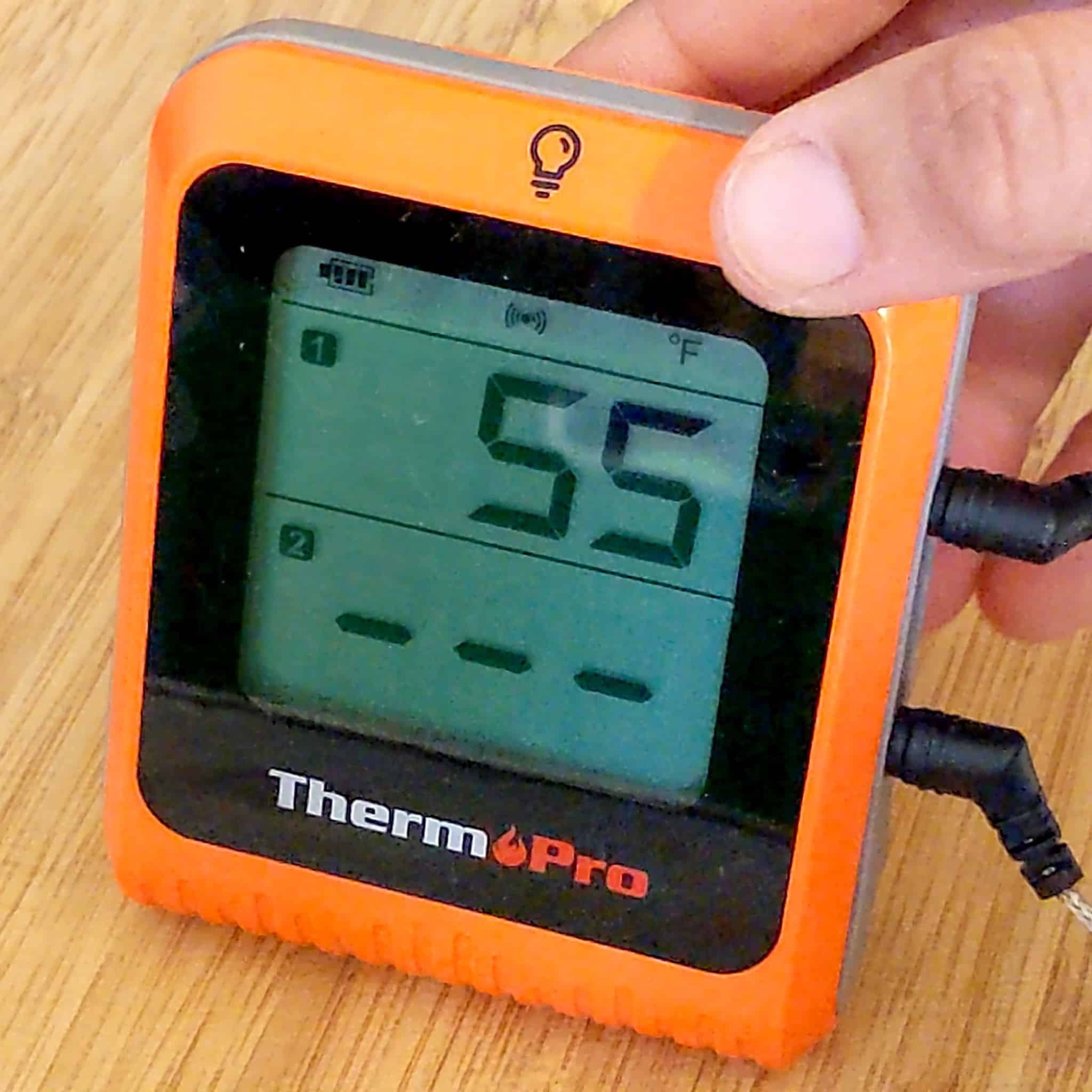ThermoPro on a cutting board with the display on showing the current chicken's temperature at 55 degrees Fahrenheit