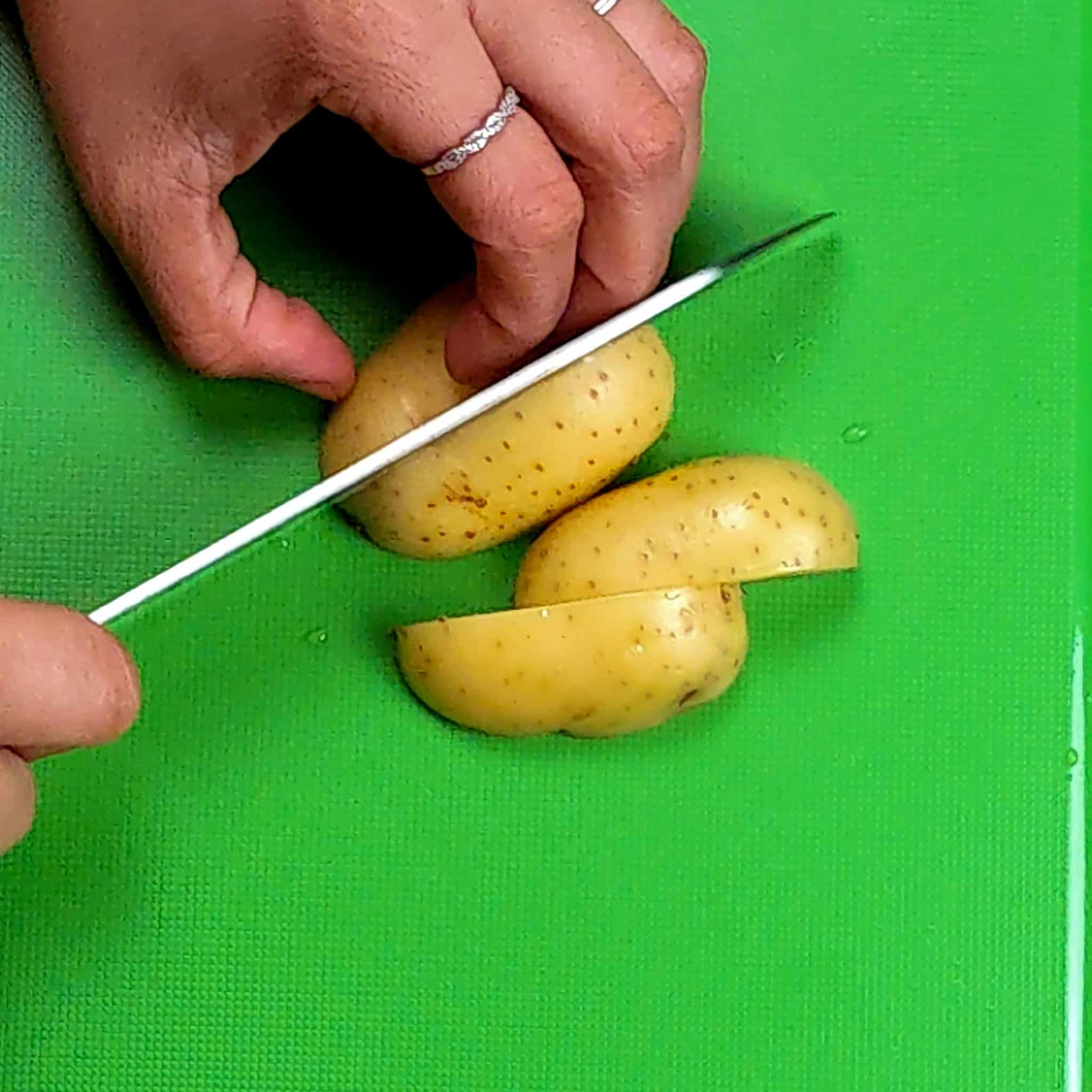 Potatoes being quartered on the a cutting board