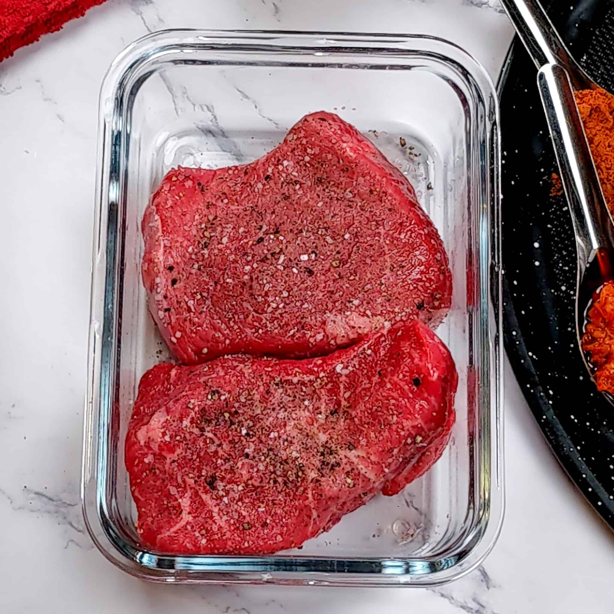 salt and pepper seasoned top sirloin steaks in a rectangle glass container