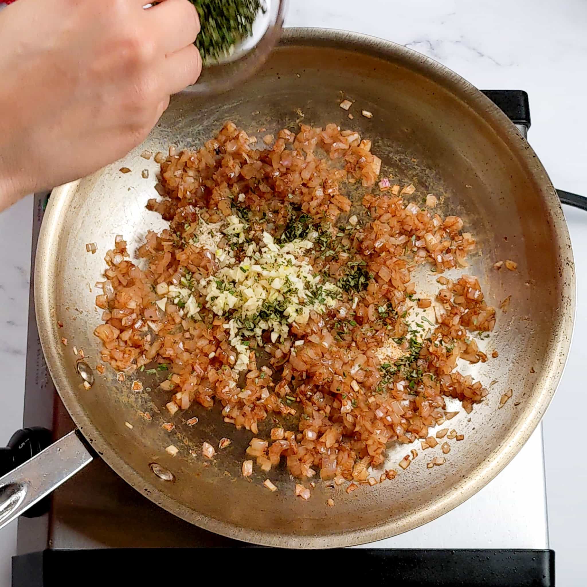 sauteed small diced shallots with chopped garlic and rosemary in a frying pan