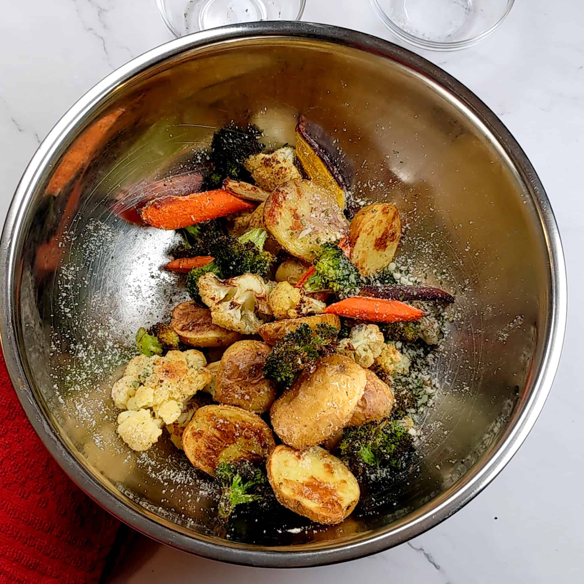 a large stainless steel bowl with roasted vegetables tossed with grated pecorino cheese and fresh chopped rosemary for Pan-Seared Sirloin Steak with Spicy Baharat Sauce recipe