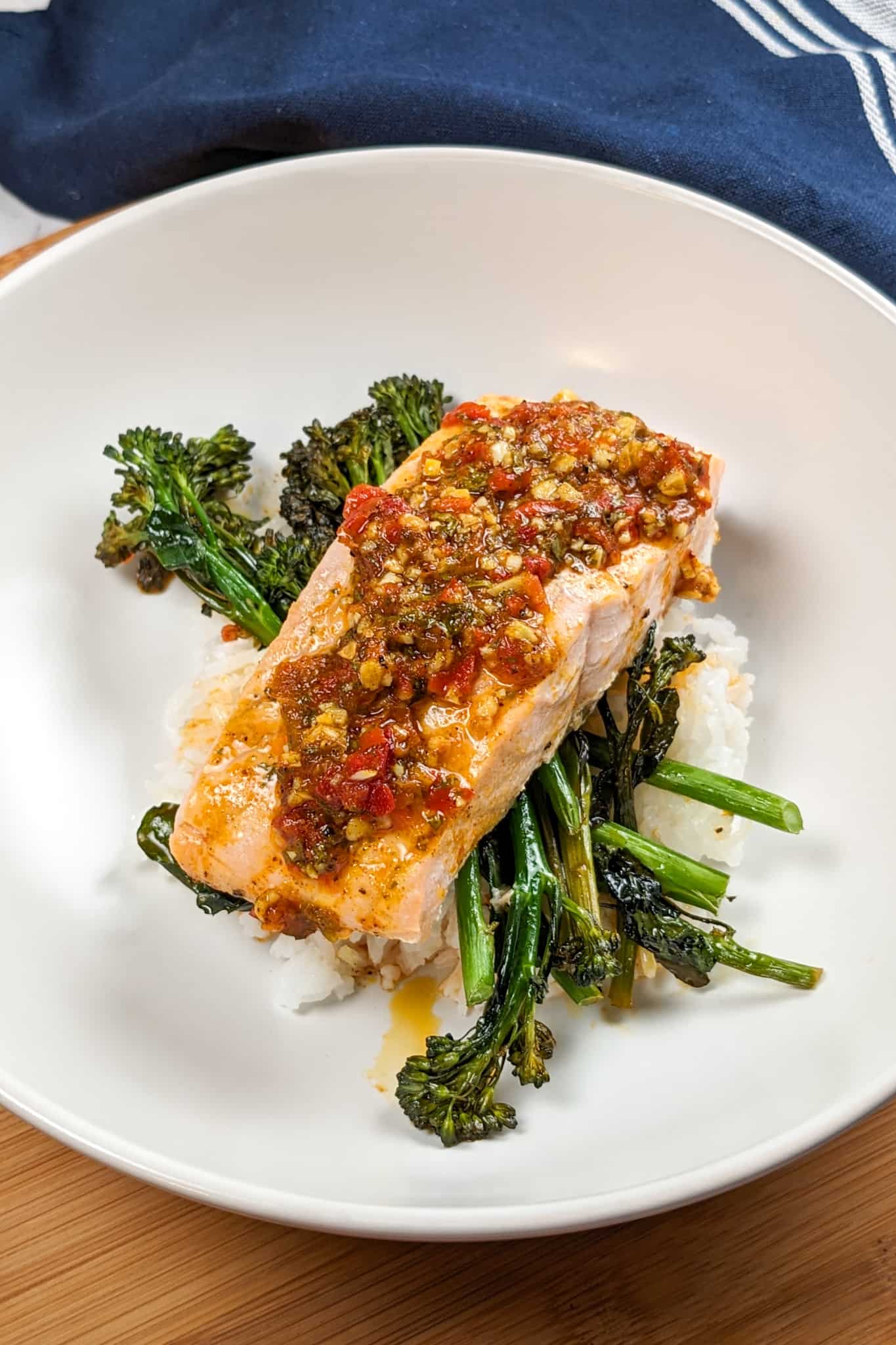 top side view of the Calabrian Pepper Basil Baked Salmon and Broccolini dish in a round wide pasta bowl.