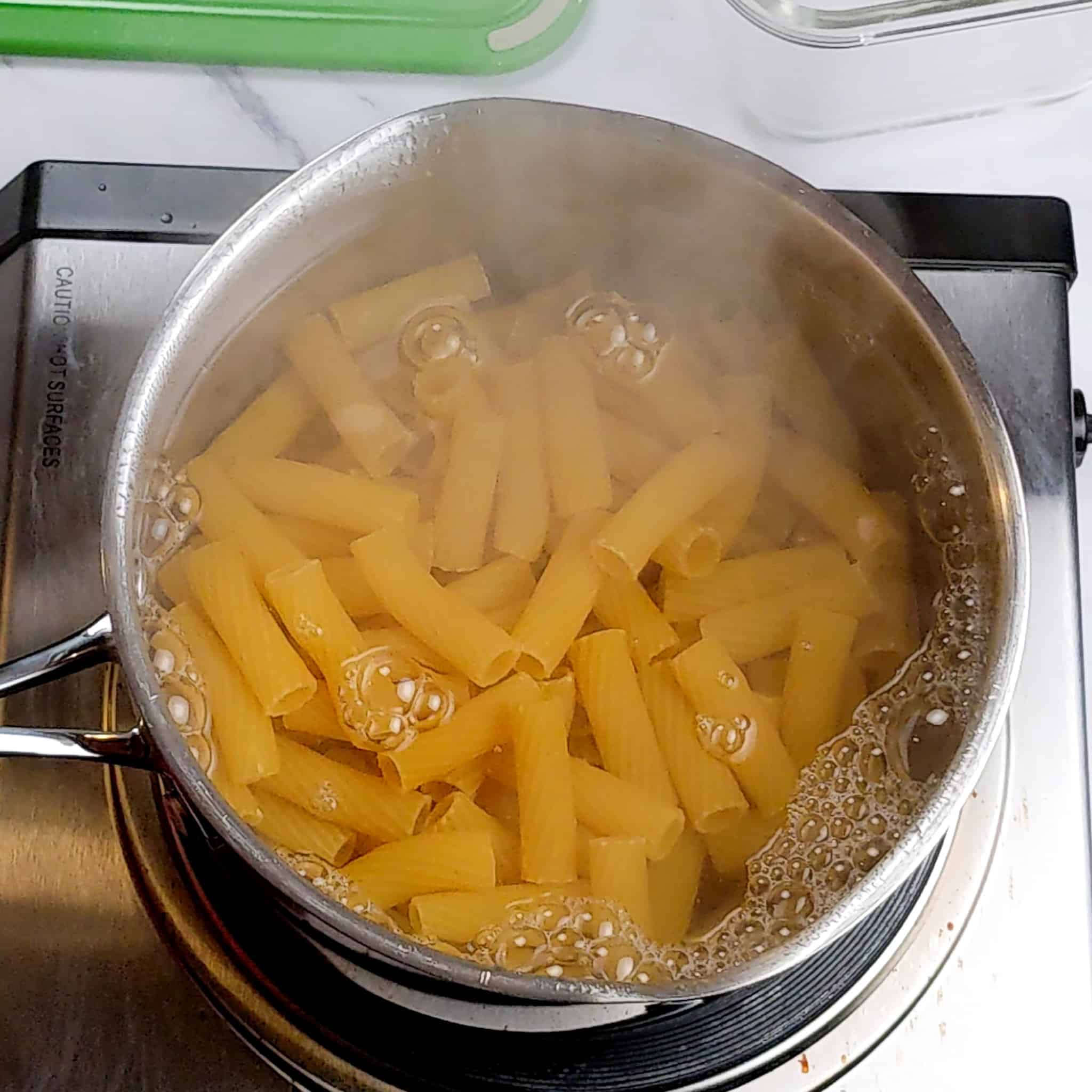 rigatoni pasta boiling in water in a pot on a stove top