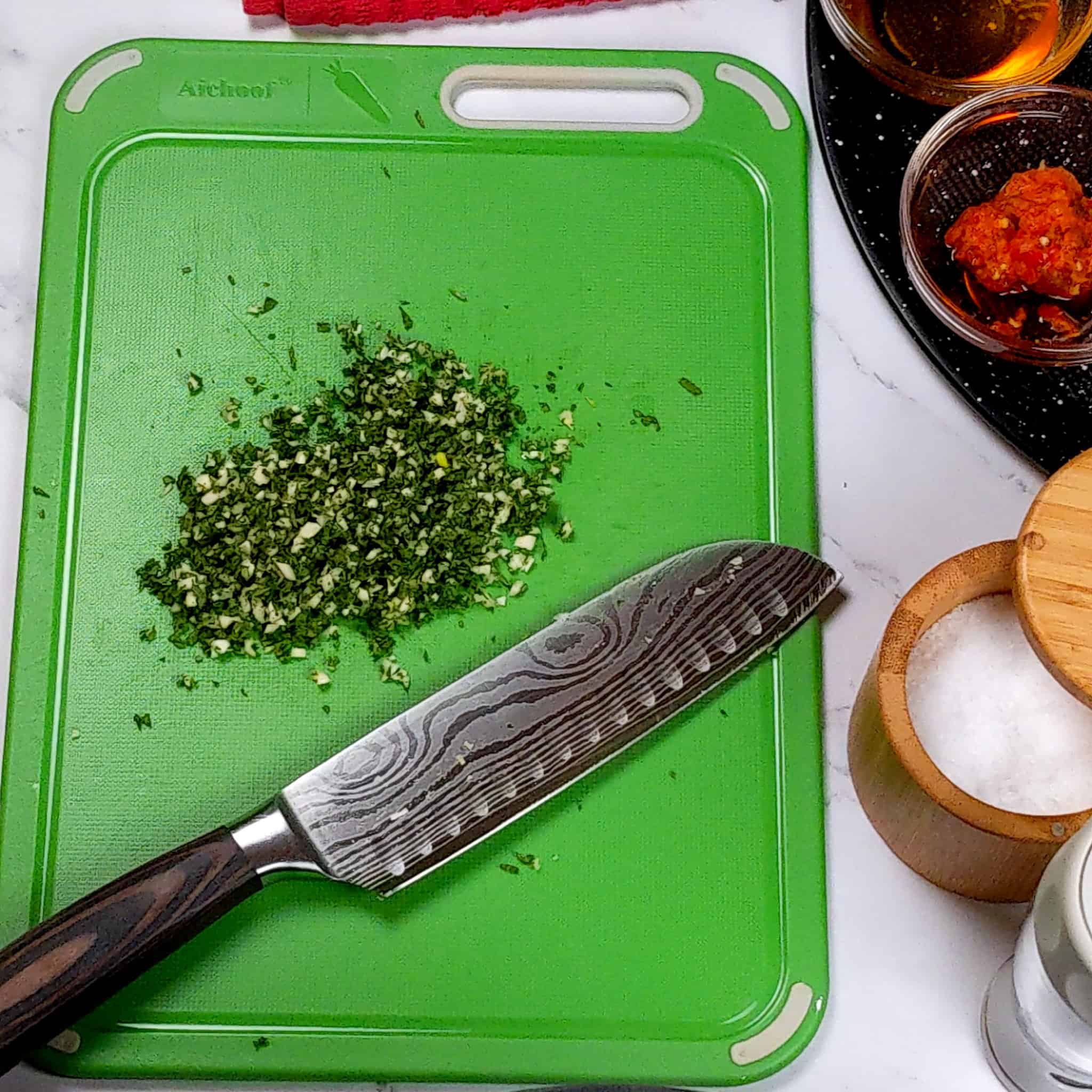 a cutting board with chopped sage and garlic mixed together in a pile next to a knife