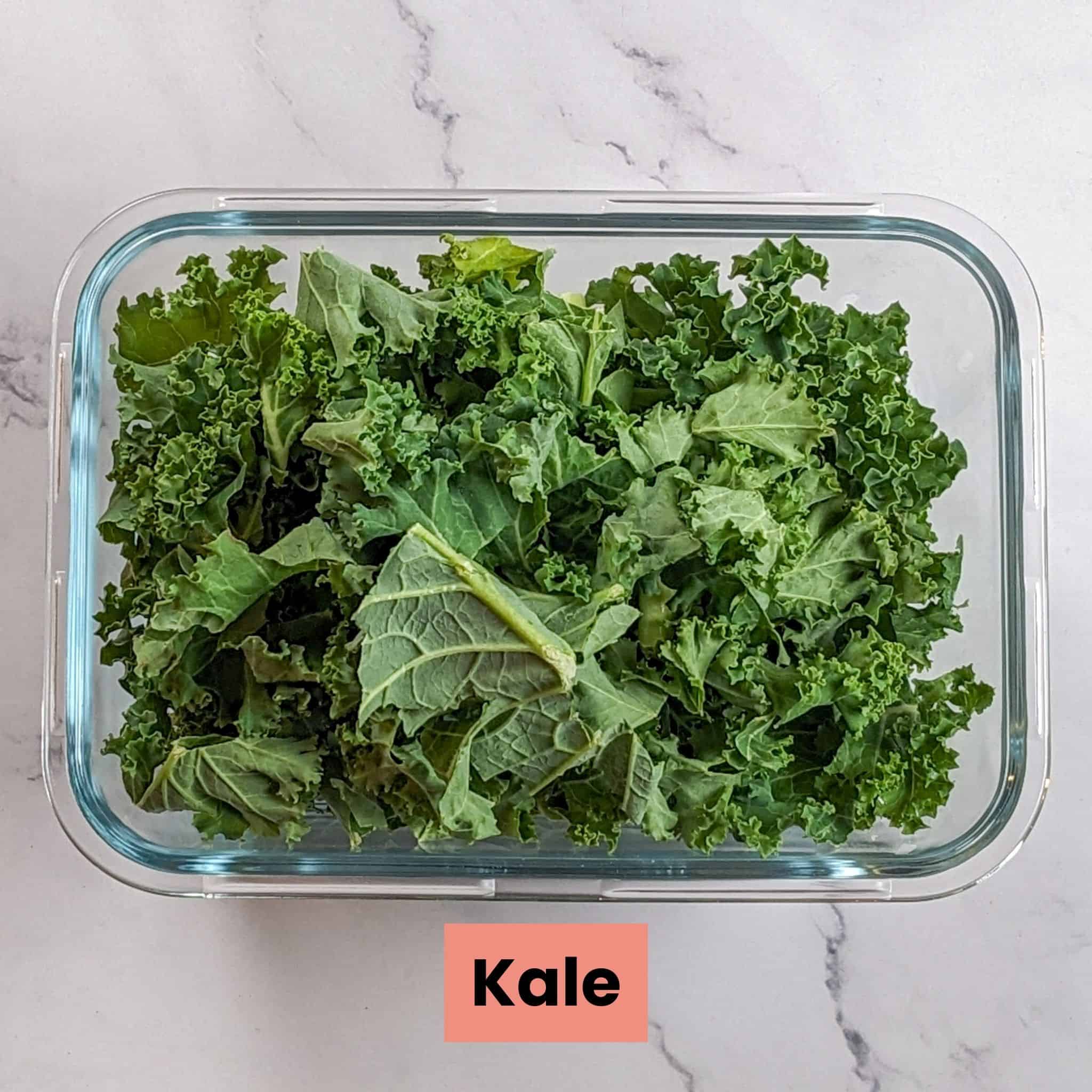 curly kale in a glass rectangle container for the bean kale tomato stew