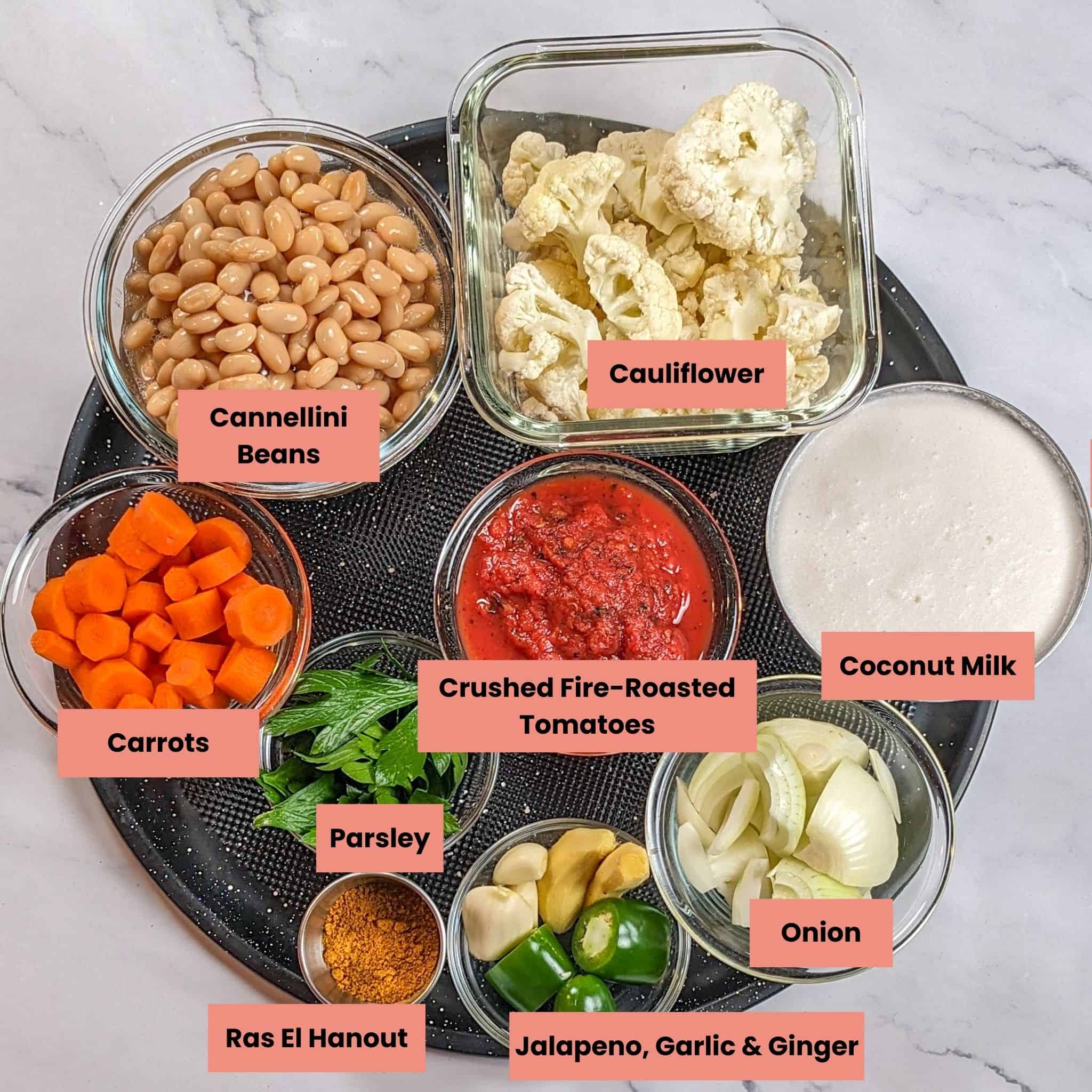 labeled Ingredients in containers on a large pizza pan for the bean kale tomato stew recipe