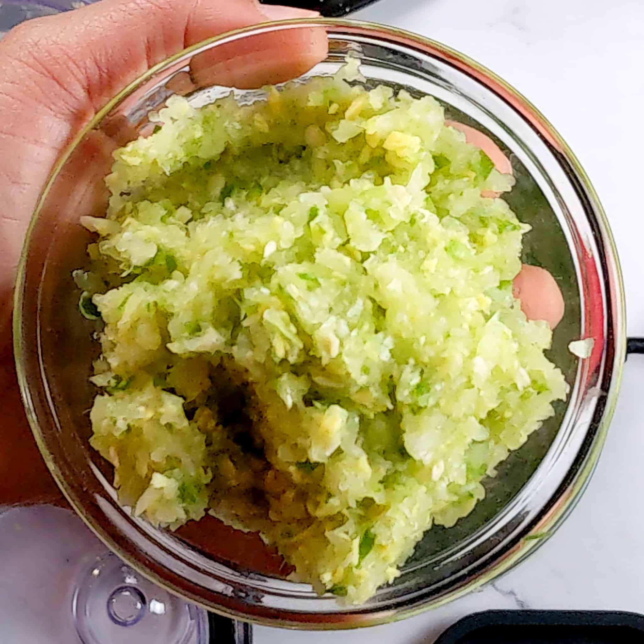 aromatic paste with garlic, ginger, onion and jalapeno in a glass bowl held in a hand