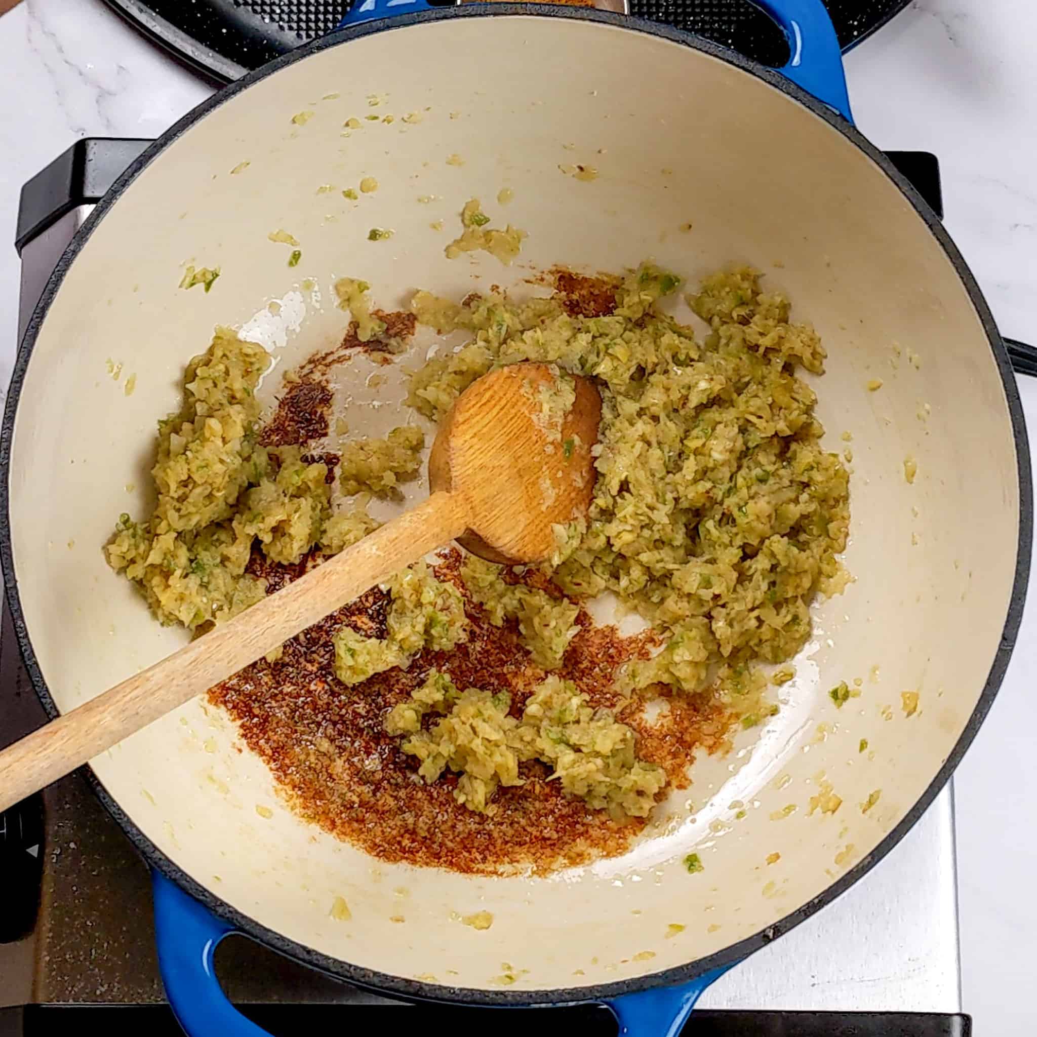 aromatic paste browning in a dutch oven with a wooden spoon