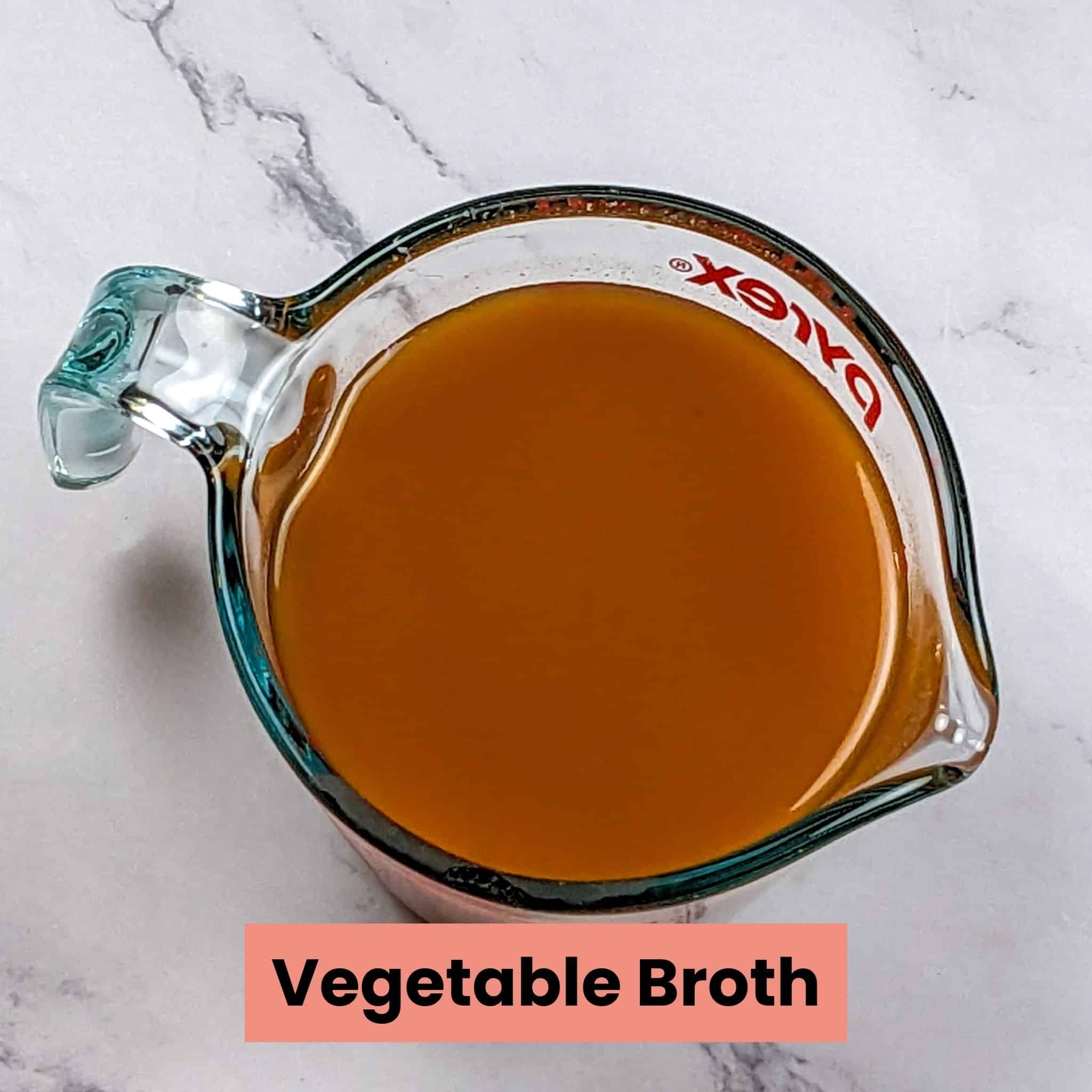 low-sodium vegetable broth in a pyrex glass measuring cup for the bean kale tomato stew