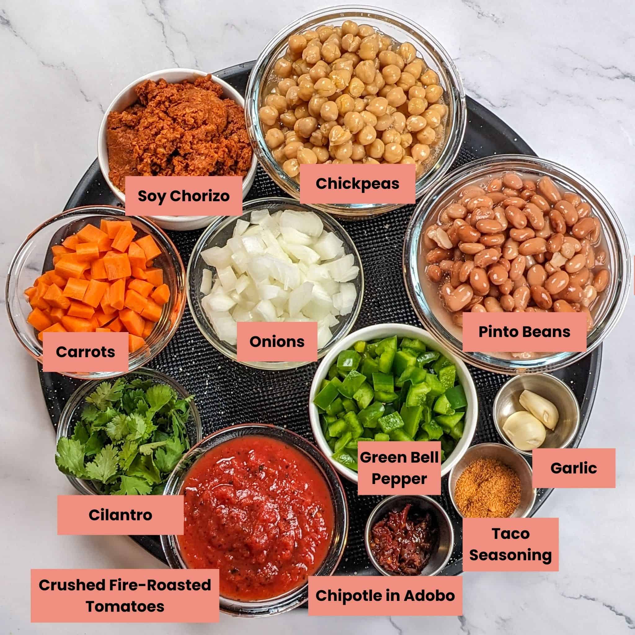 labeled ingredients for the chorizo bean chipotle stew in containers on a round large pizza pan