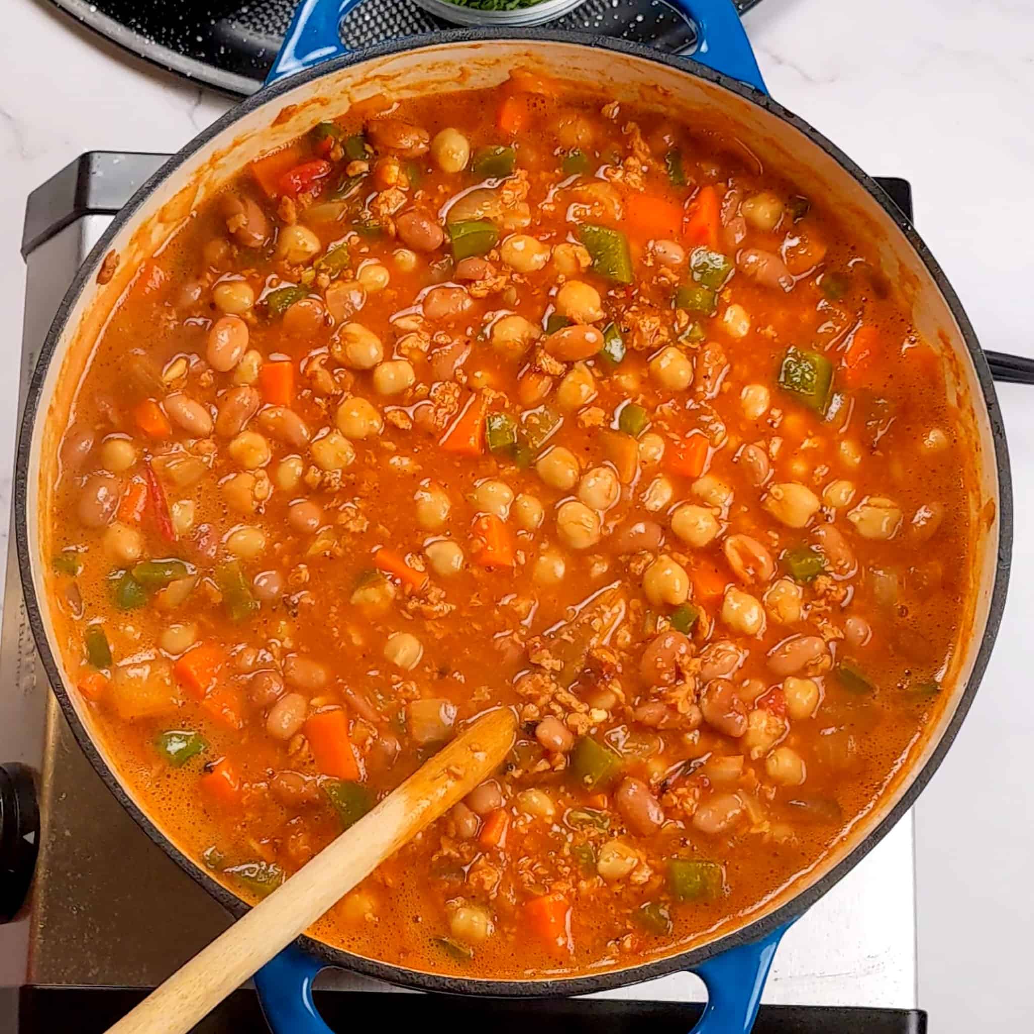the chorizo bean chipotle stew in a dutch oven with a wooden spoon