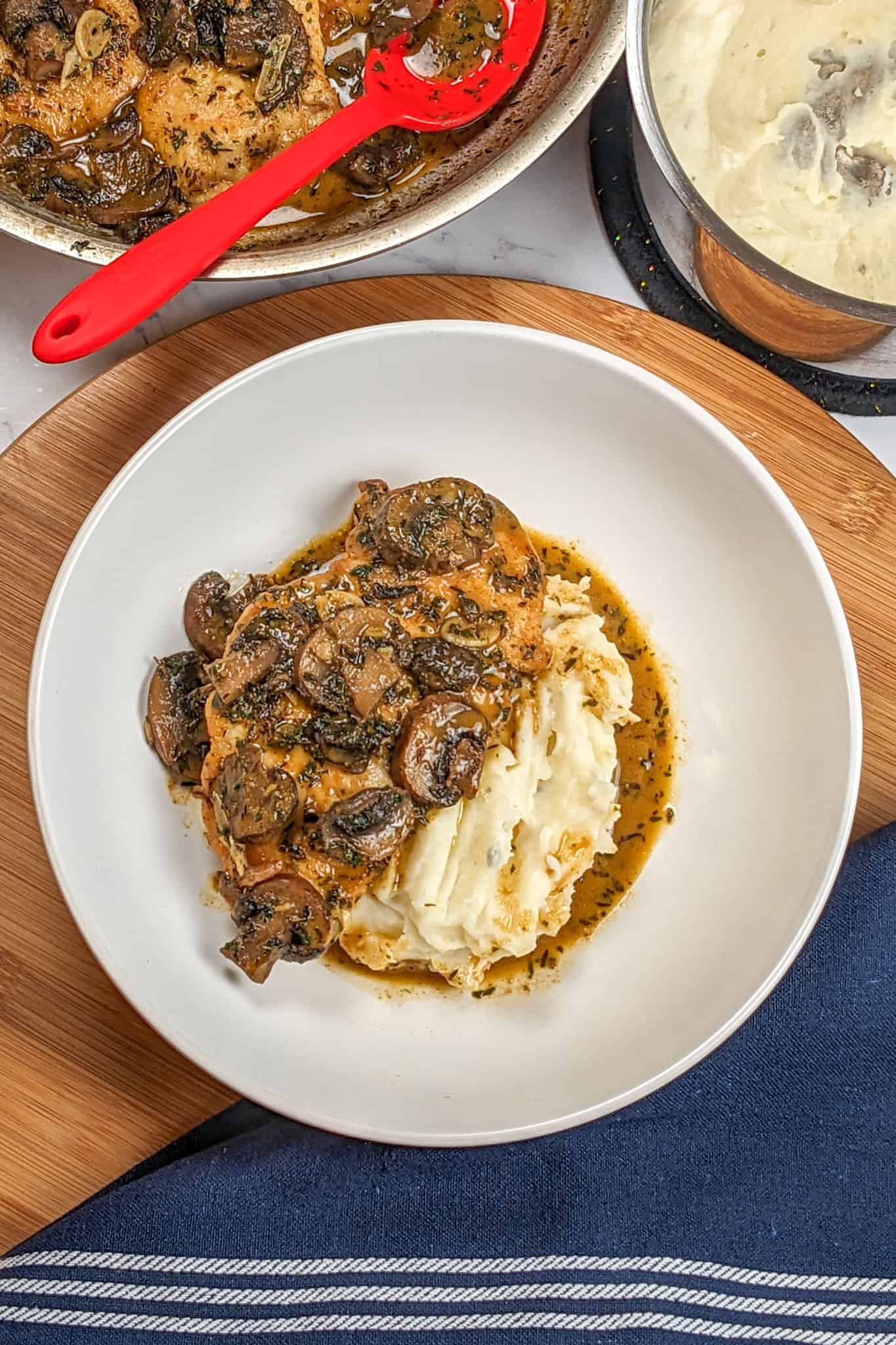 top view of Easy Spicy Creamy Coconut Mushroom Chicken with Rum on a lazy susan next to a kitchen towel, pan of mushroom chicken and pot of mashed potatoes