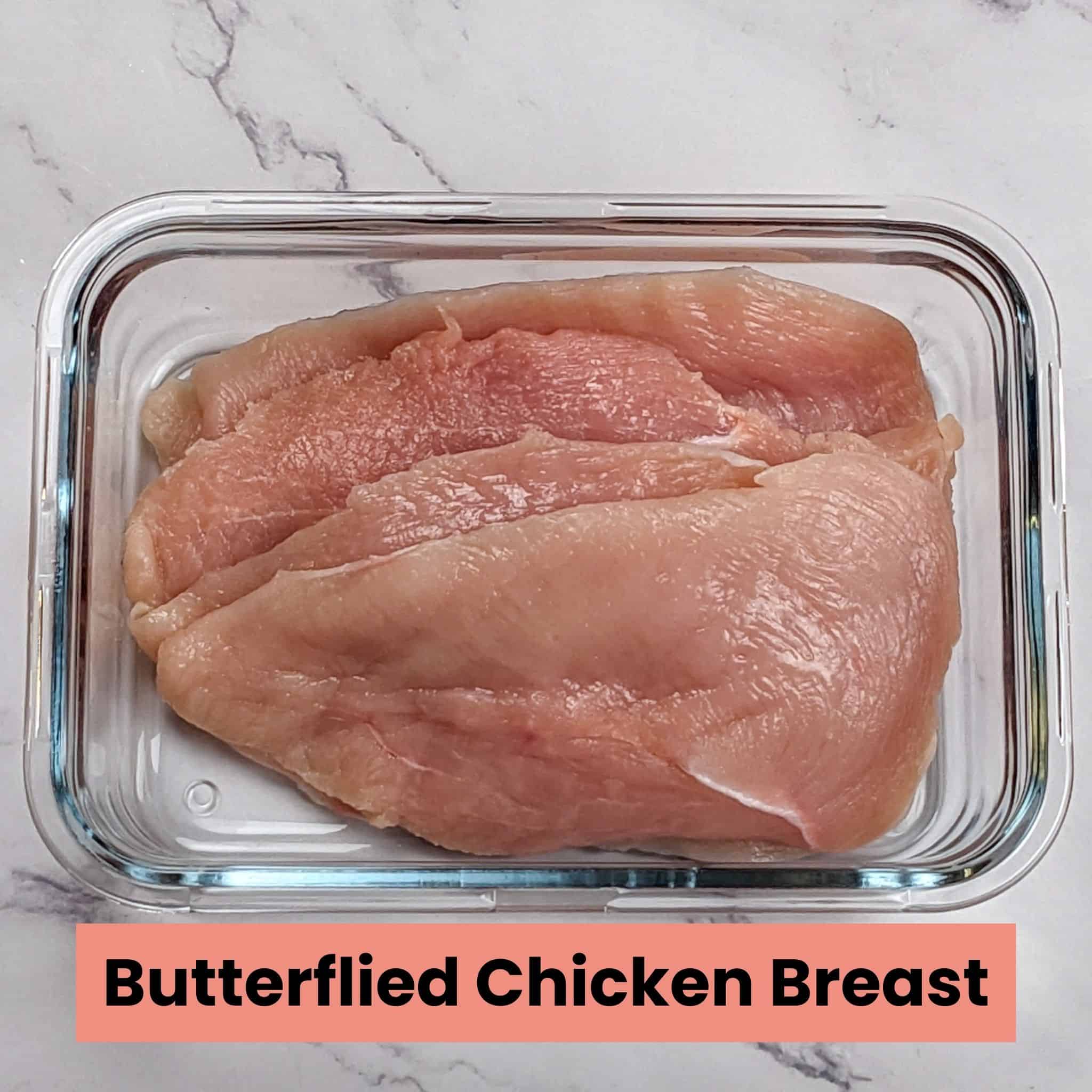 butterflied chicken breasts in a rectangle glass container