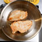 pan seared butterflied chicken in oil in an all-clad frying pan