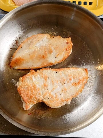 pan seared butterflied chicken in oil in an all-clad frying pan