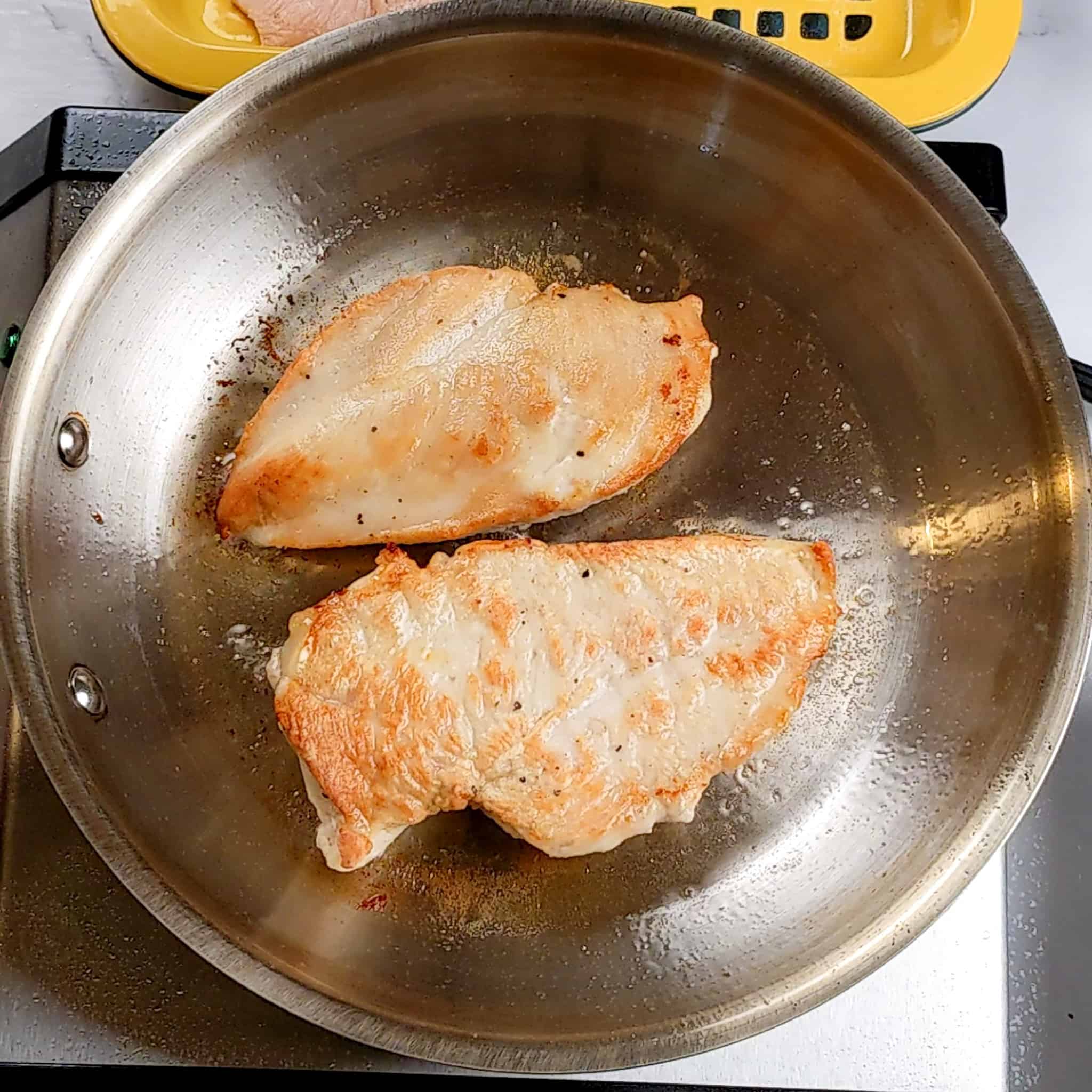 pan seared butterflied chicken in oil in an all-clad frying pan