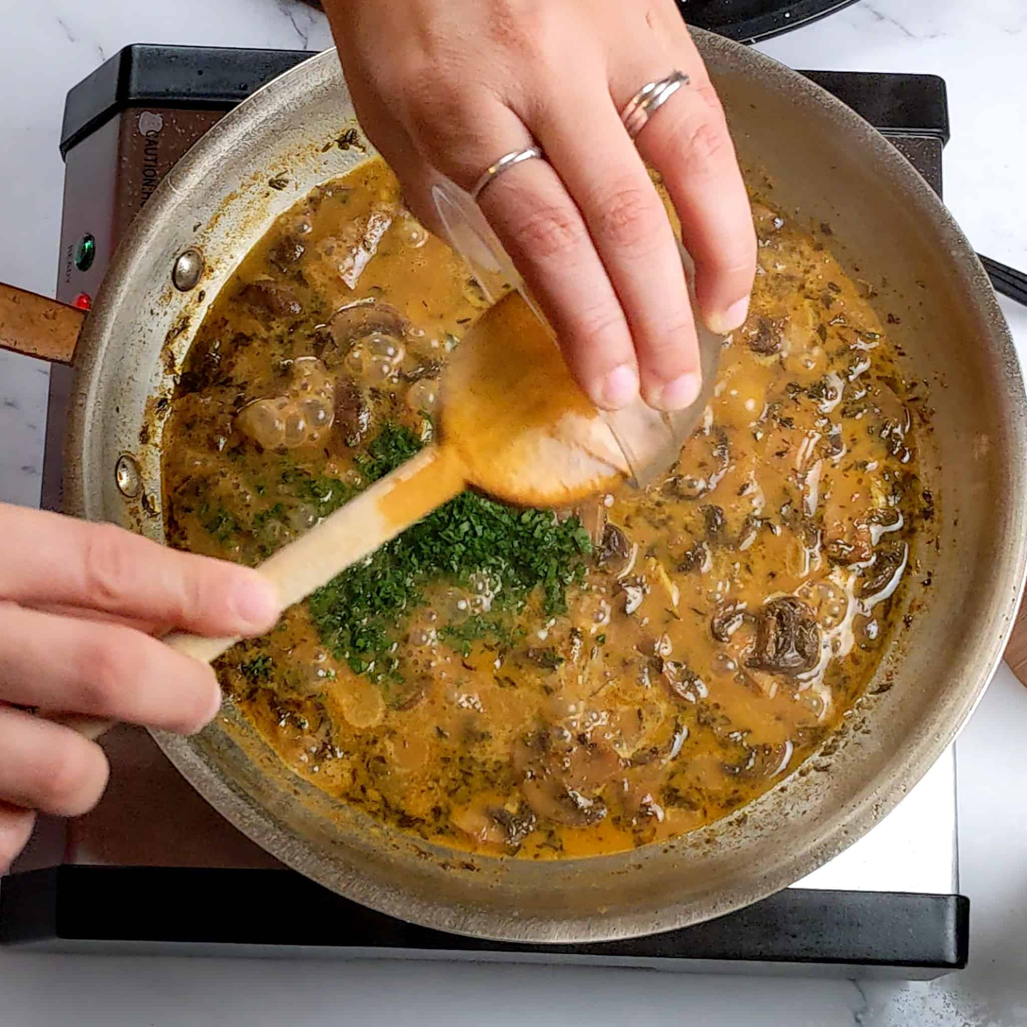 chopped fresh parsley being added to the creamy coconut milk mushroom broth