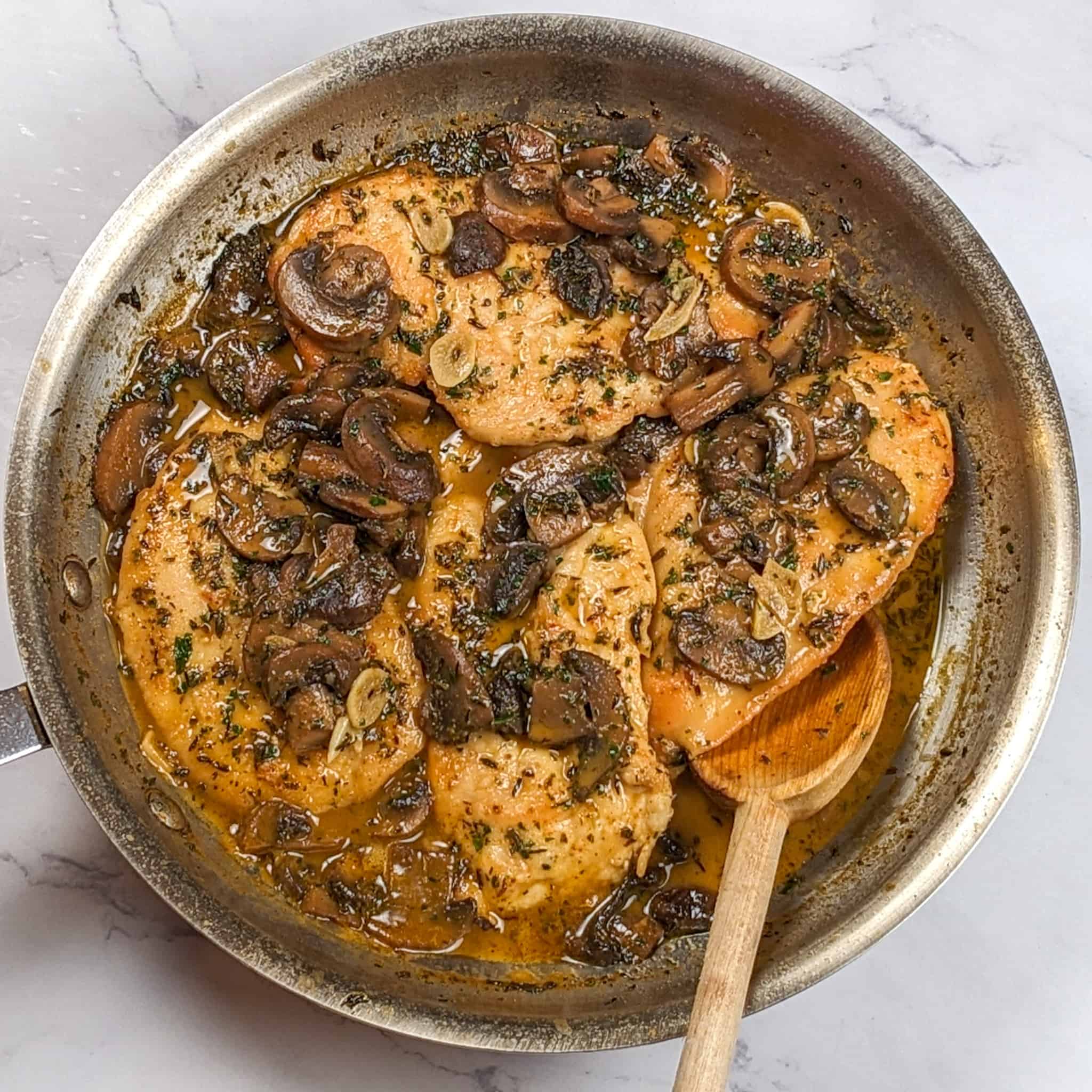 butterflied chicken breast and sliced mushrooms in a creamy dark broth in an all-clad frying pan