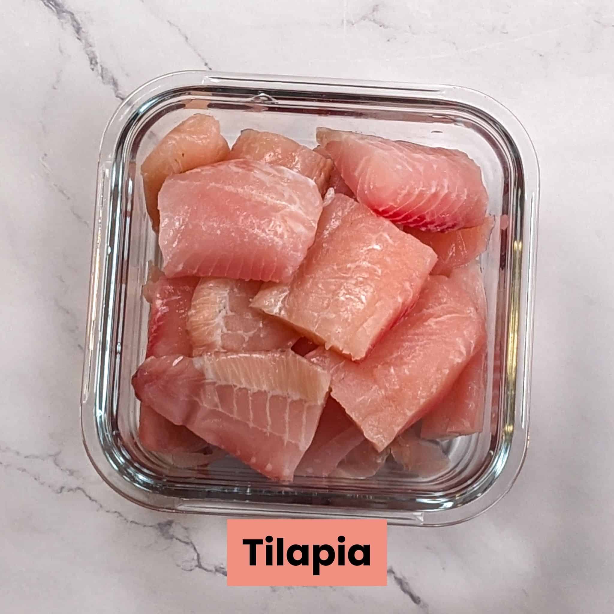 large chunks of tilapia fish in a square clear glass food container