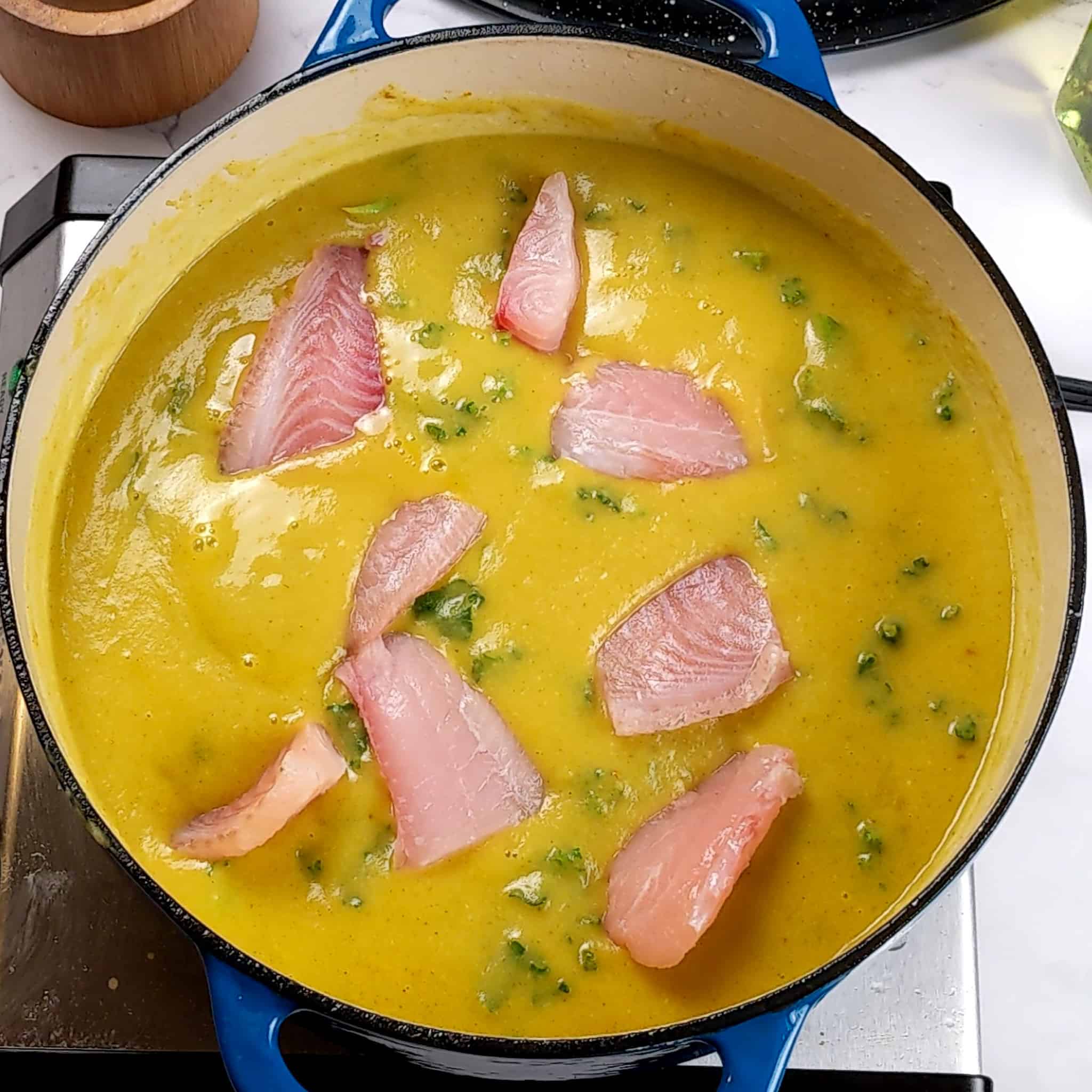 fresh tilapia fish chunks added to the creamy curry potato coconut and kale soup for the Best Fragrant Creamy Potato Coconut Curry Fish Soup recipe