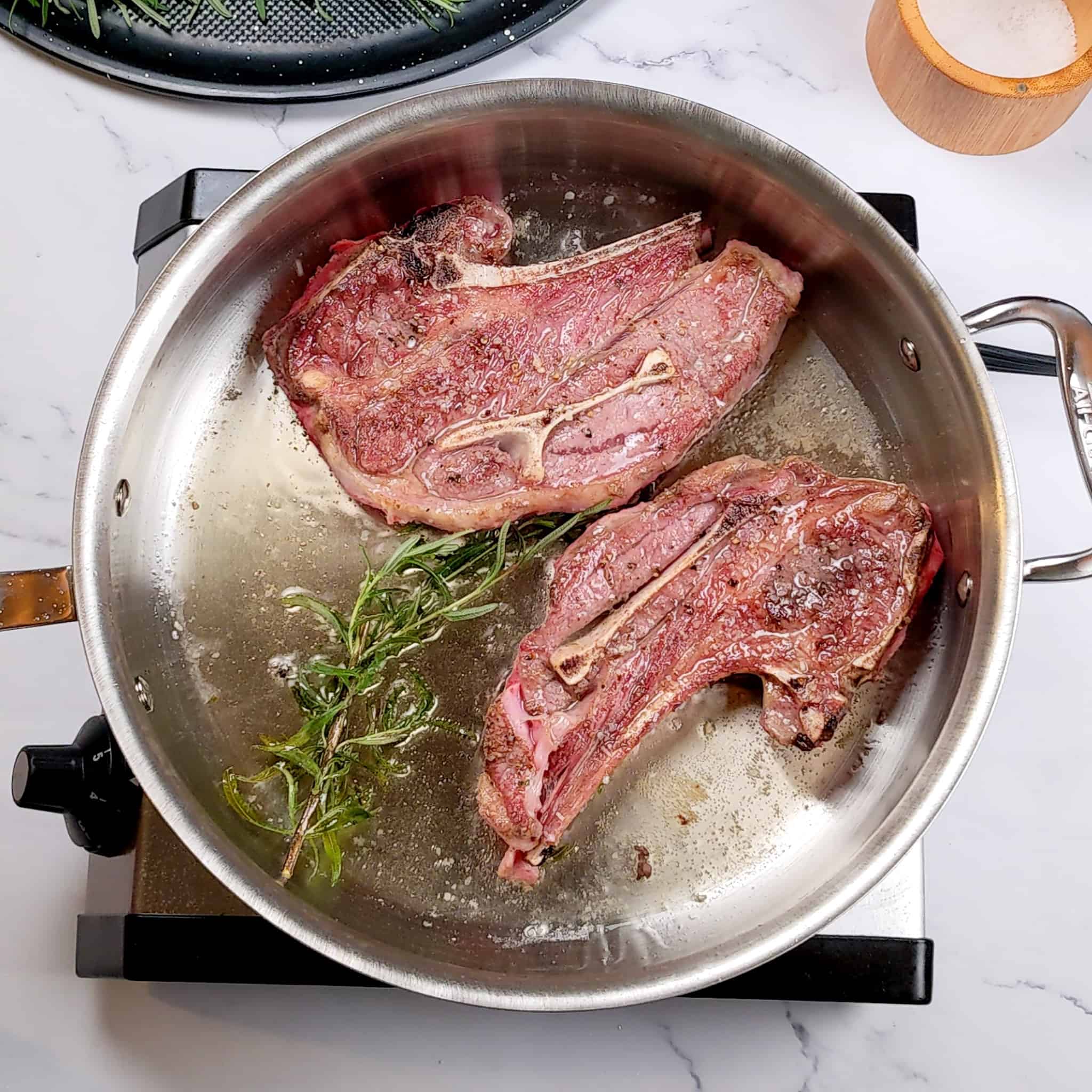 seared lamb shoulder chops in an all-clad stainless steel saute pan for the Quick and Easy Lean Baharat Spiced Bean and Lamb Stew recipe.