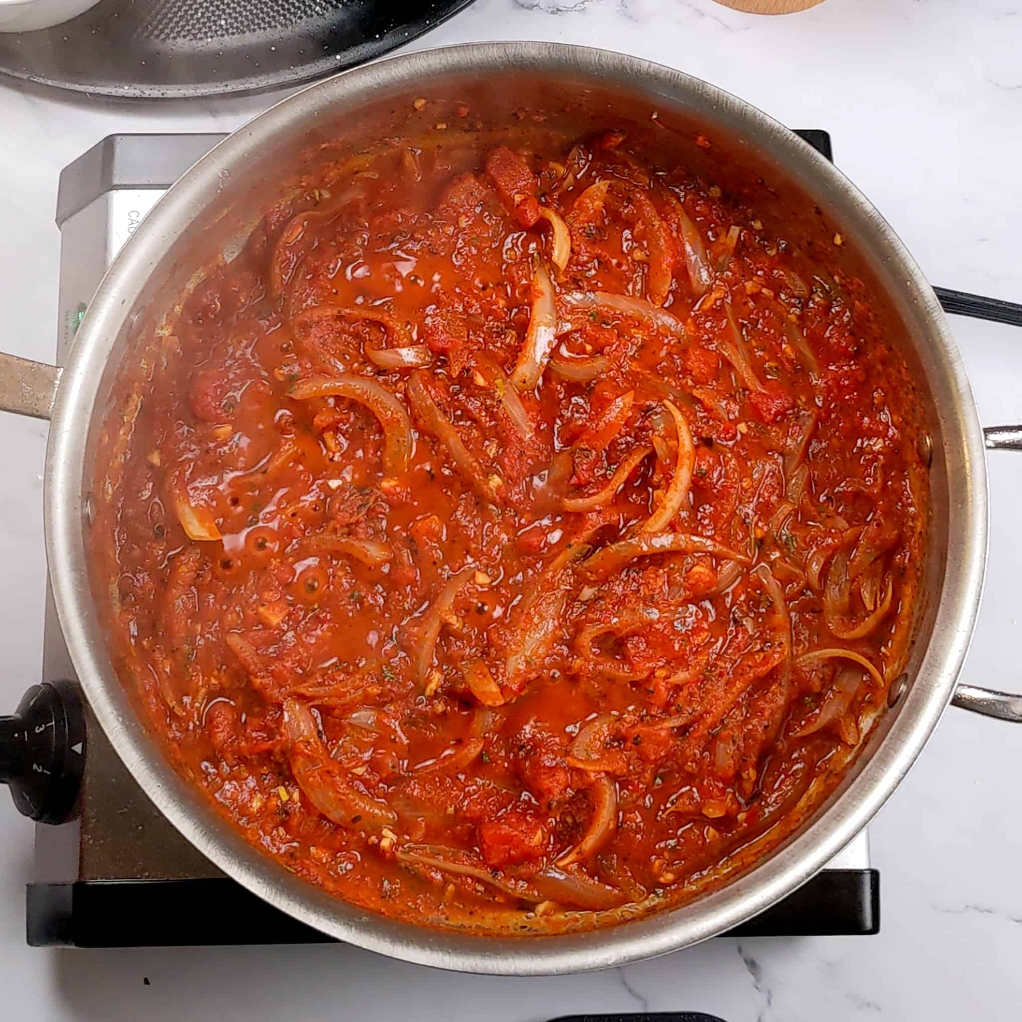 sauted onions with tomato sauce, harissa paste and seasoning in an all-clad stainless steel saute pan