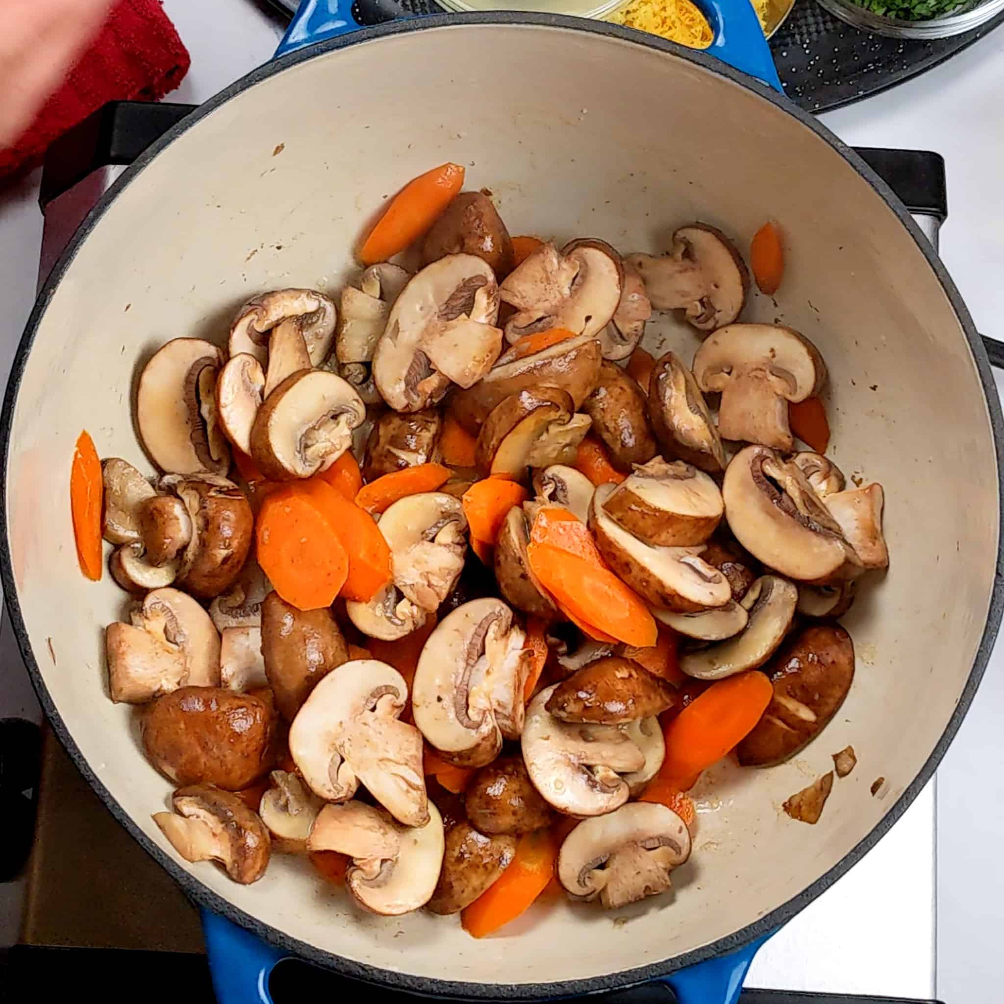 sauteed sliced mushrooms and carrots in a Dutch oven