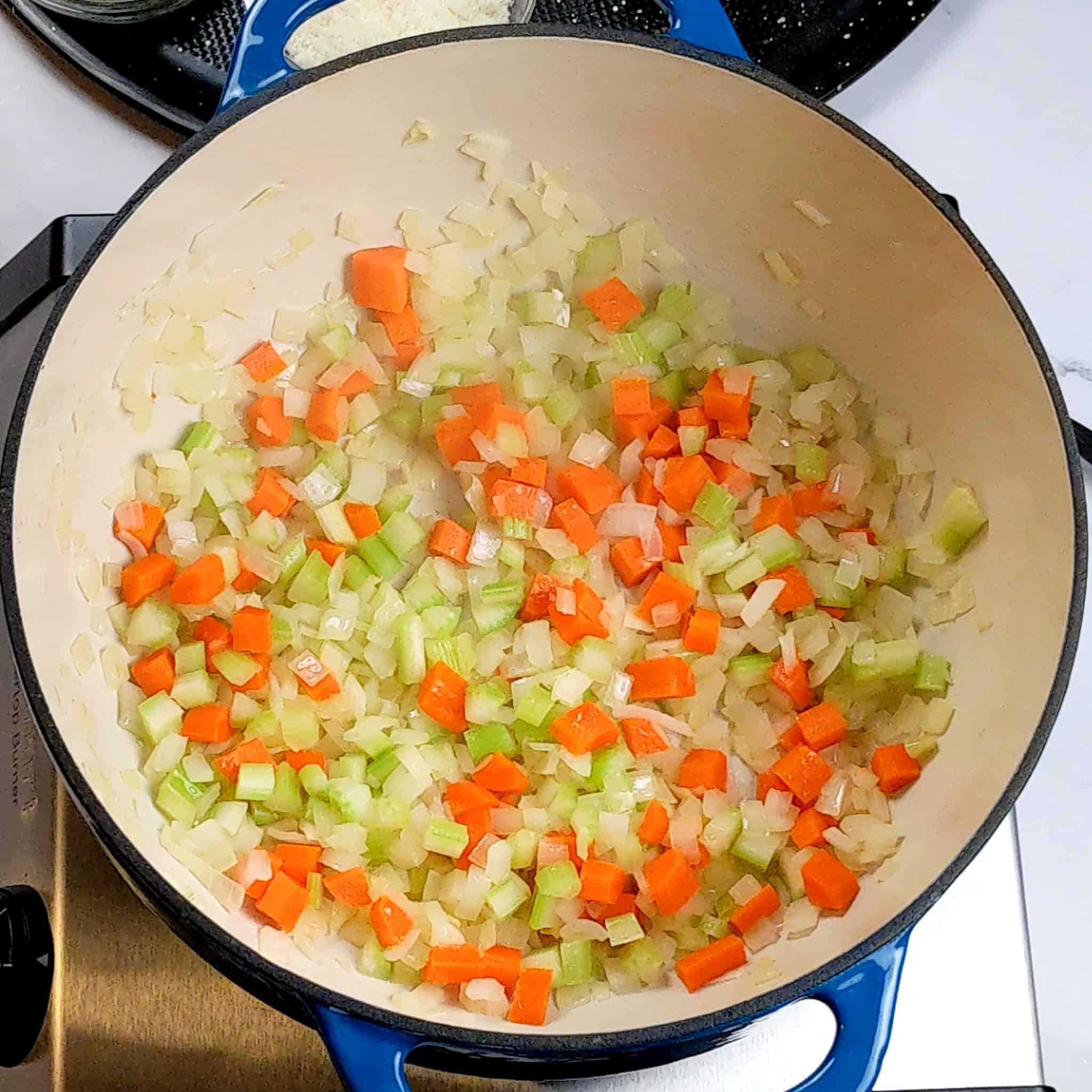 A mirepoix of onions, carrots and celery sweating in a dutch oven