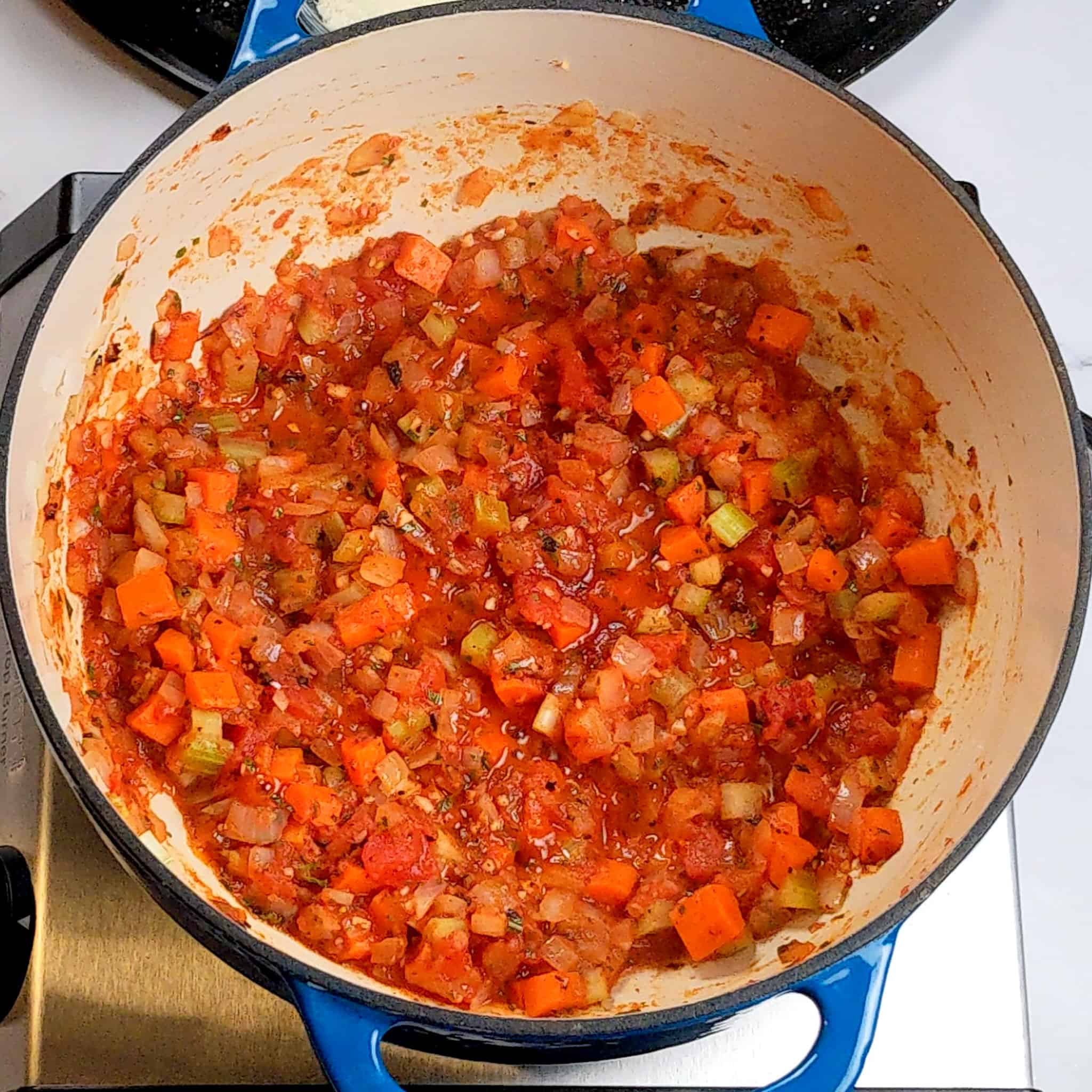diced mirepoix combined with crushed fire-roasted tomatoes and crushed calabrian peppers in a dutch oven