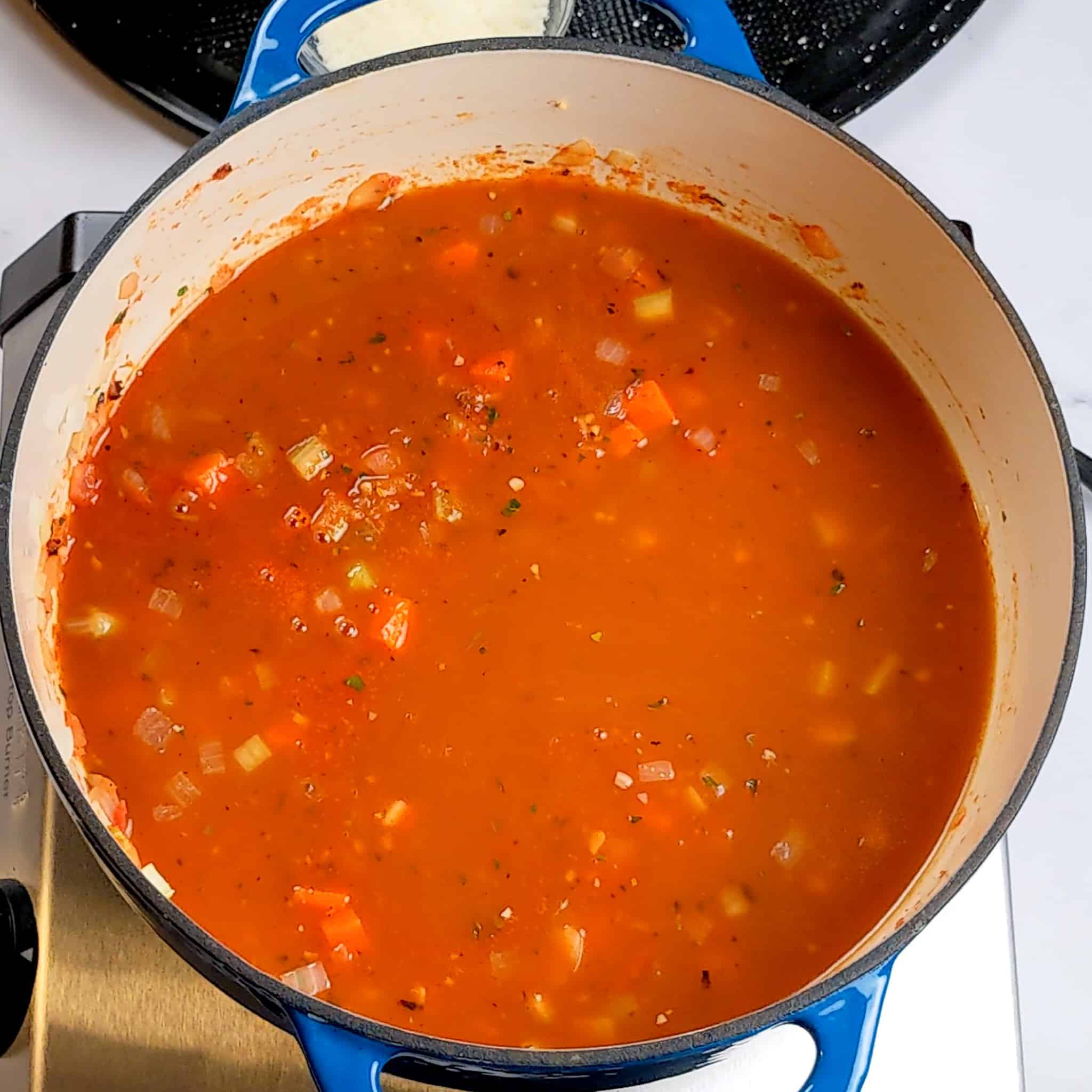 vegetable broth added to a mixture of mirepoix in tomatoes and peppers for the macaroni cheese tomato stew recipe