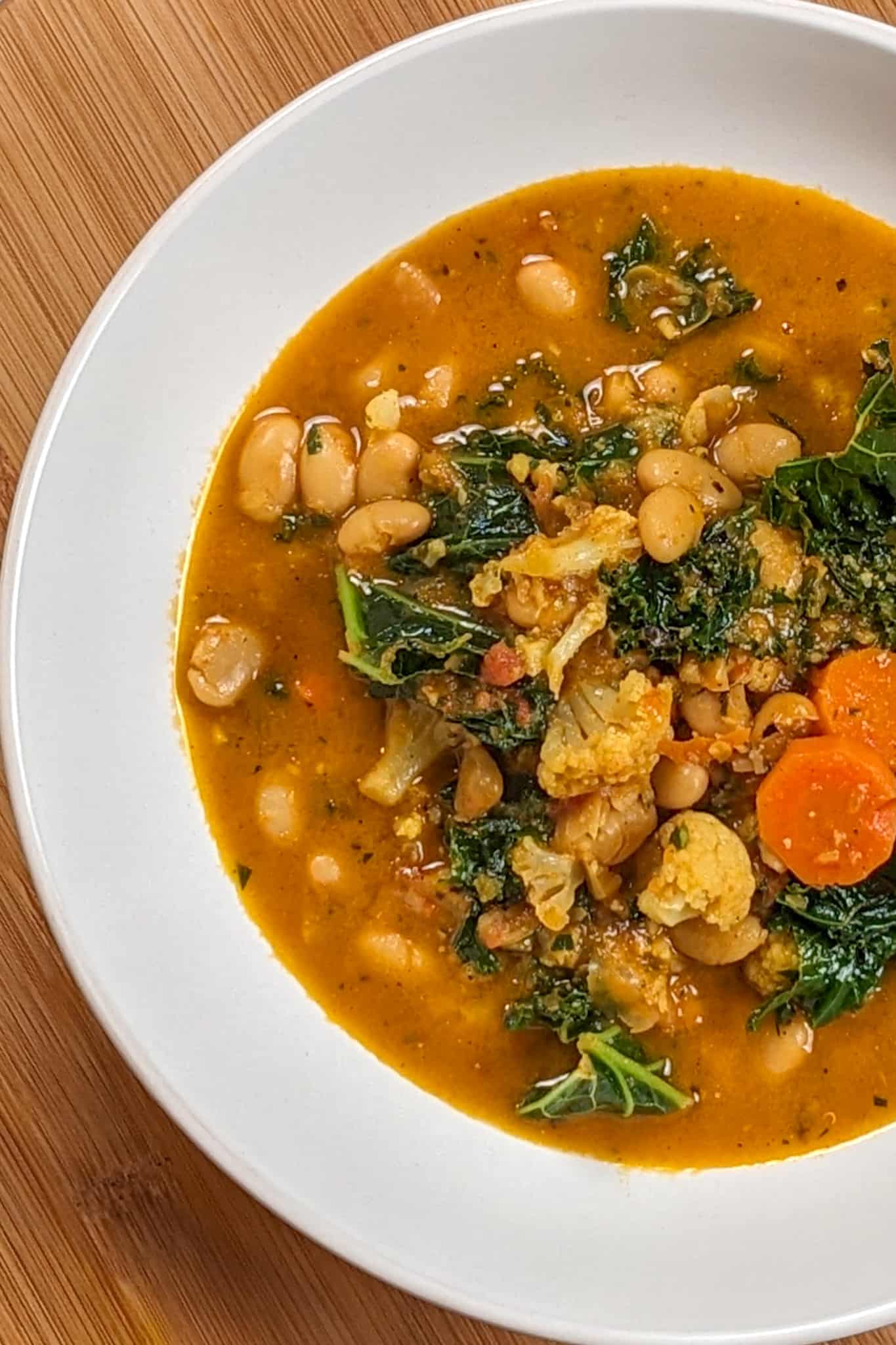 top view of the bean kale tomato stew in a wide rim bowl