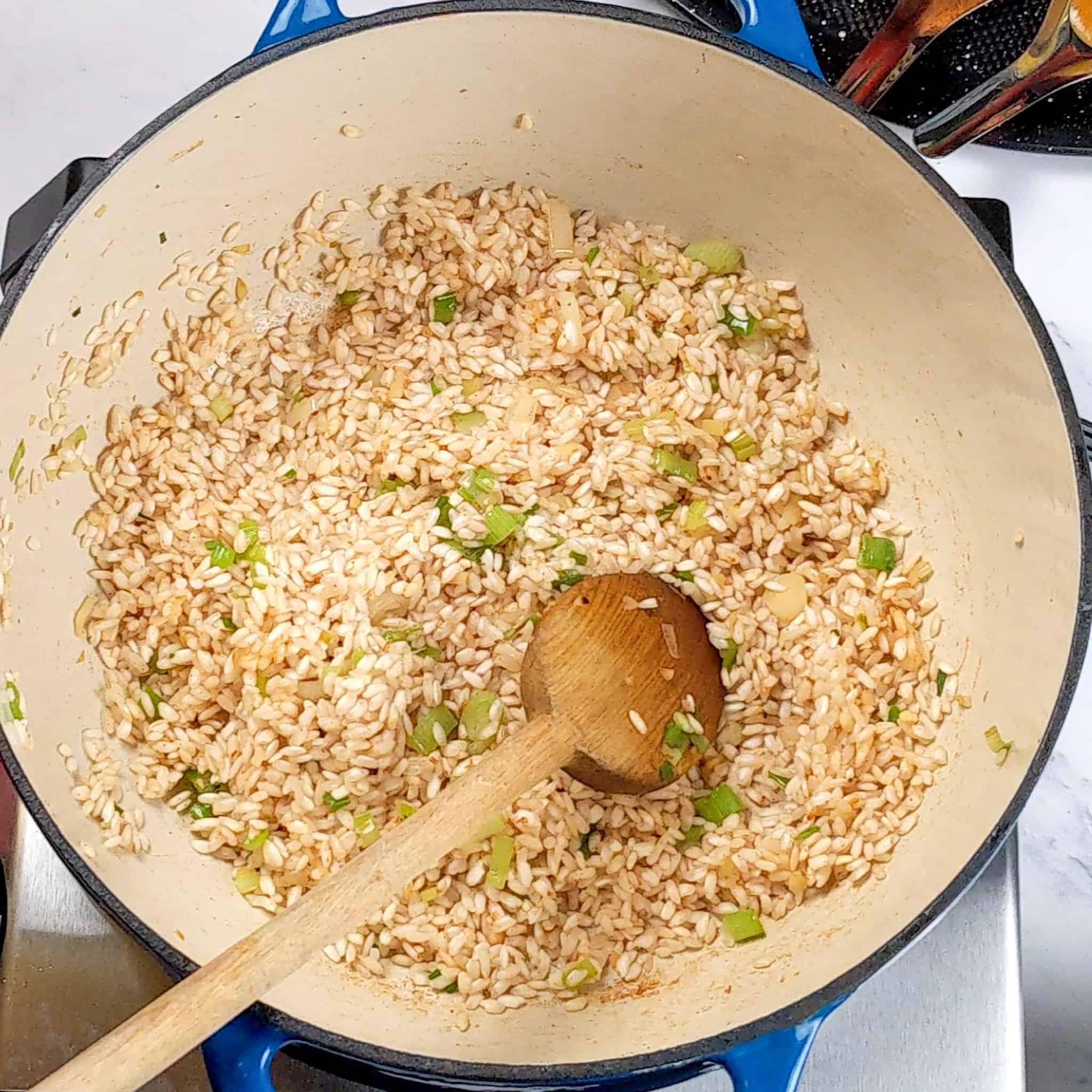 toasted arborio rice mixed with bacon fat, cooked sliced scallions and chopped garlic in an dutch oven with a wooden spoon