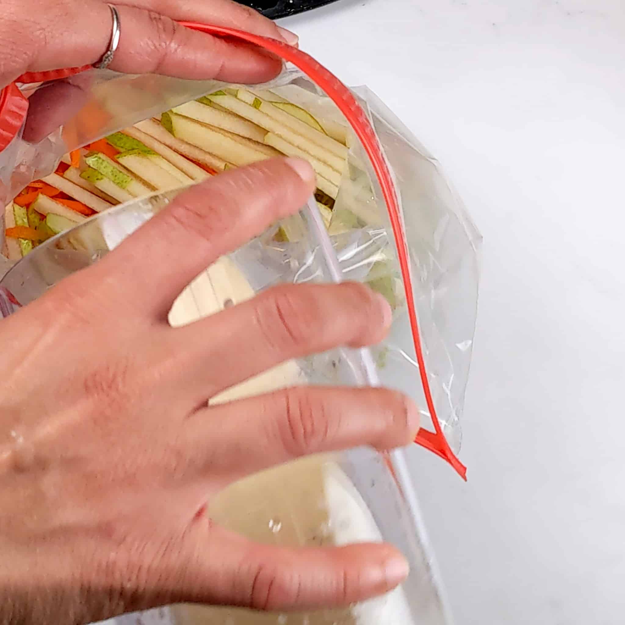 vinaigrette being pour into the a sealable bag of shredded vegetables and fruits for the Crispy Air Fryer Honey Jerk Rubbed Chicken Wings recipe