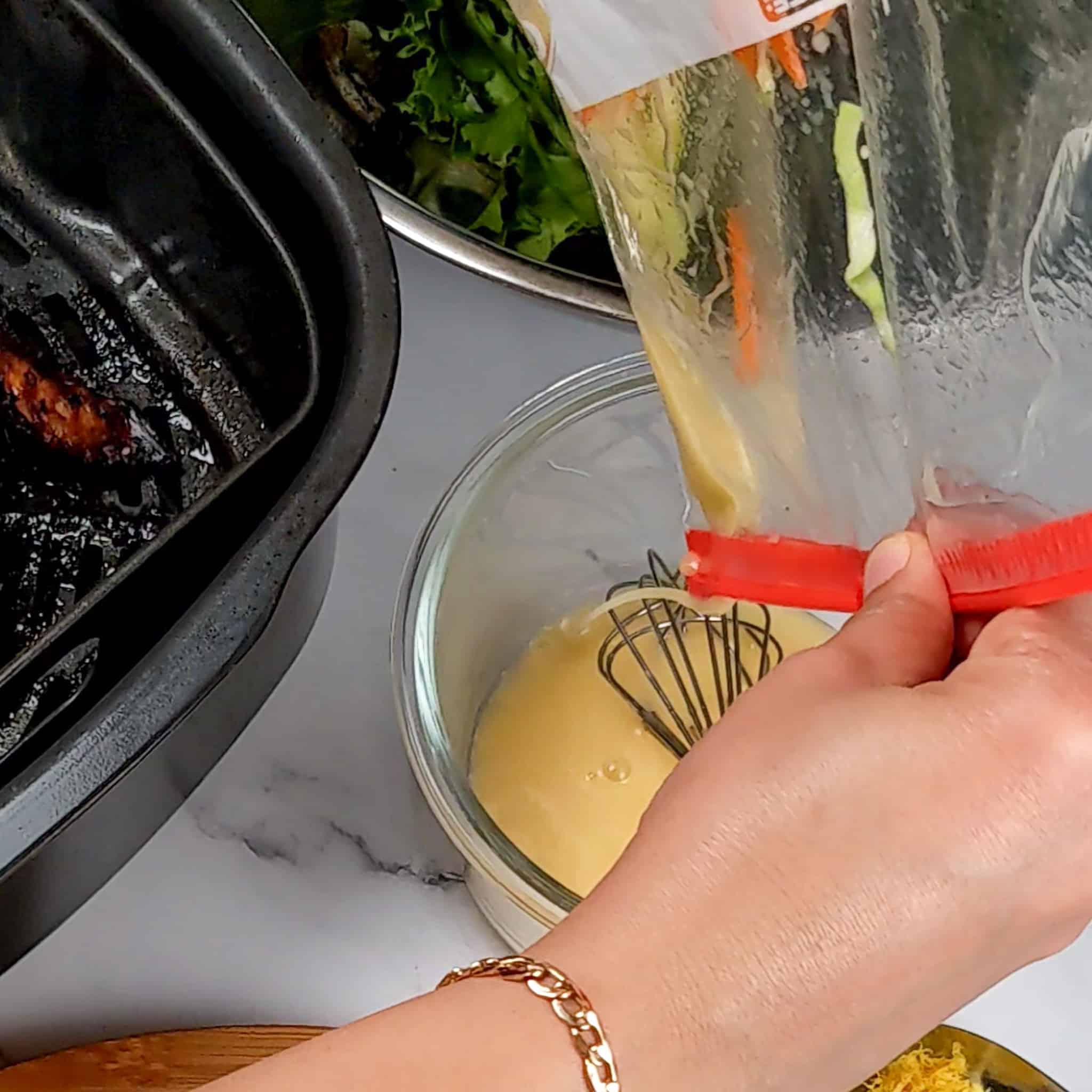 the vinaigrette being poured out of the bag of the marinated shredded salad mix