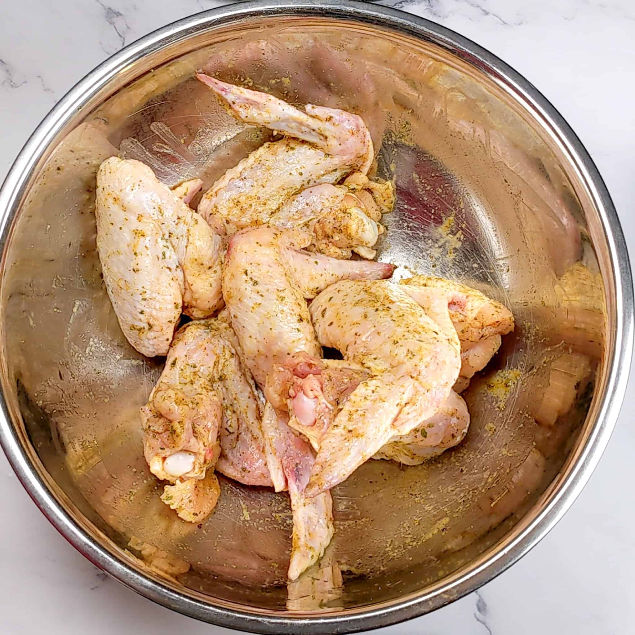 seasoned raw whole chicken wings in a stainless steel bowl