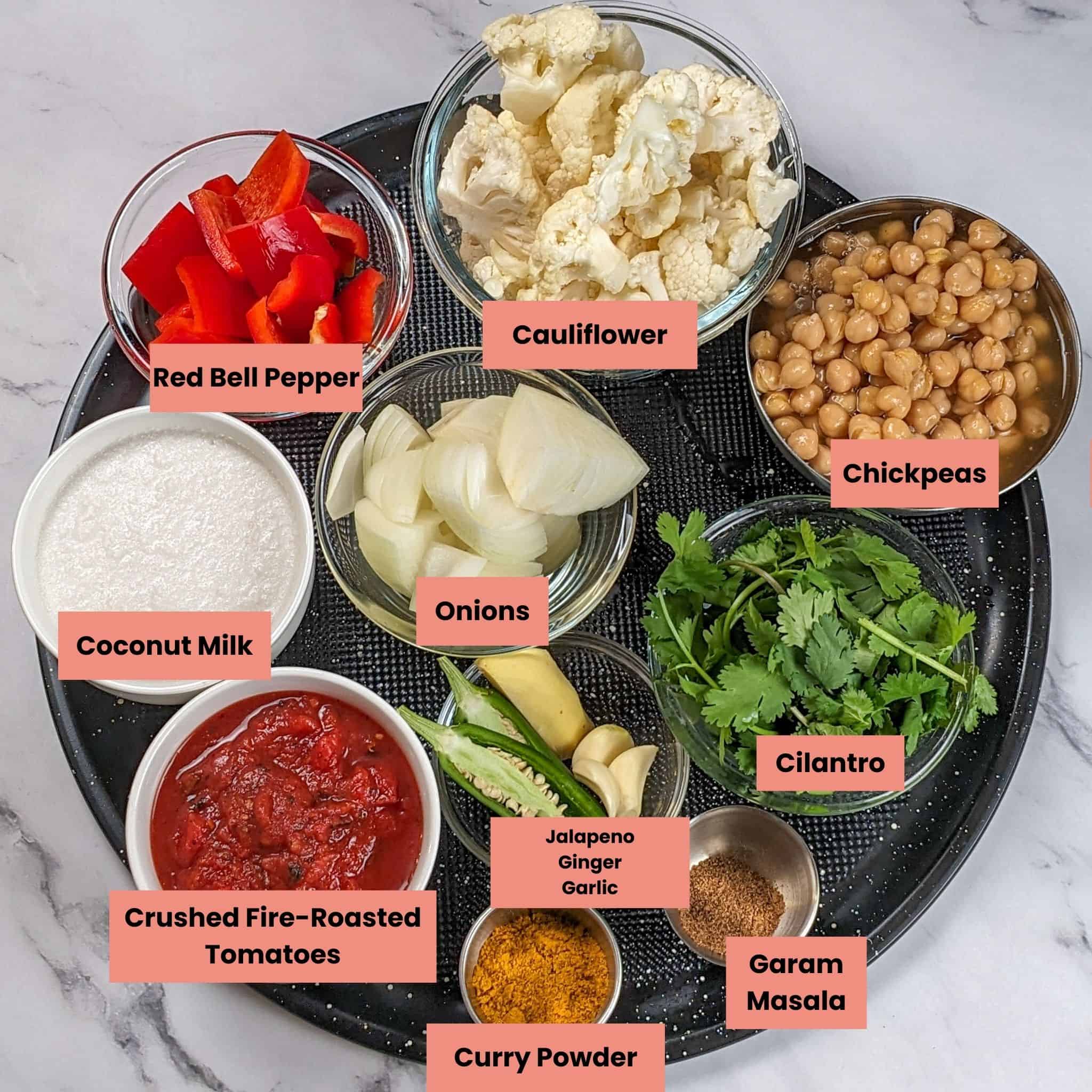 the ingredients for the Air Fryer Roasted Chicken Chickpeas Vegetable Curry recipe in containers on a large round pizza pan.