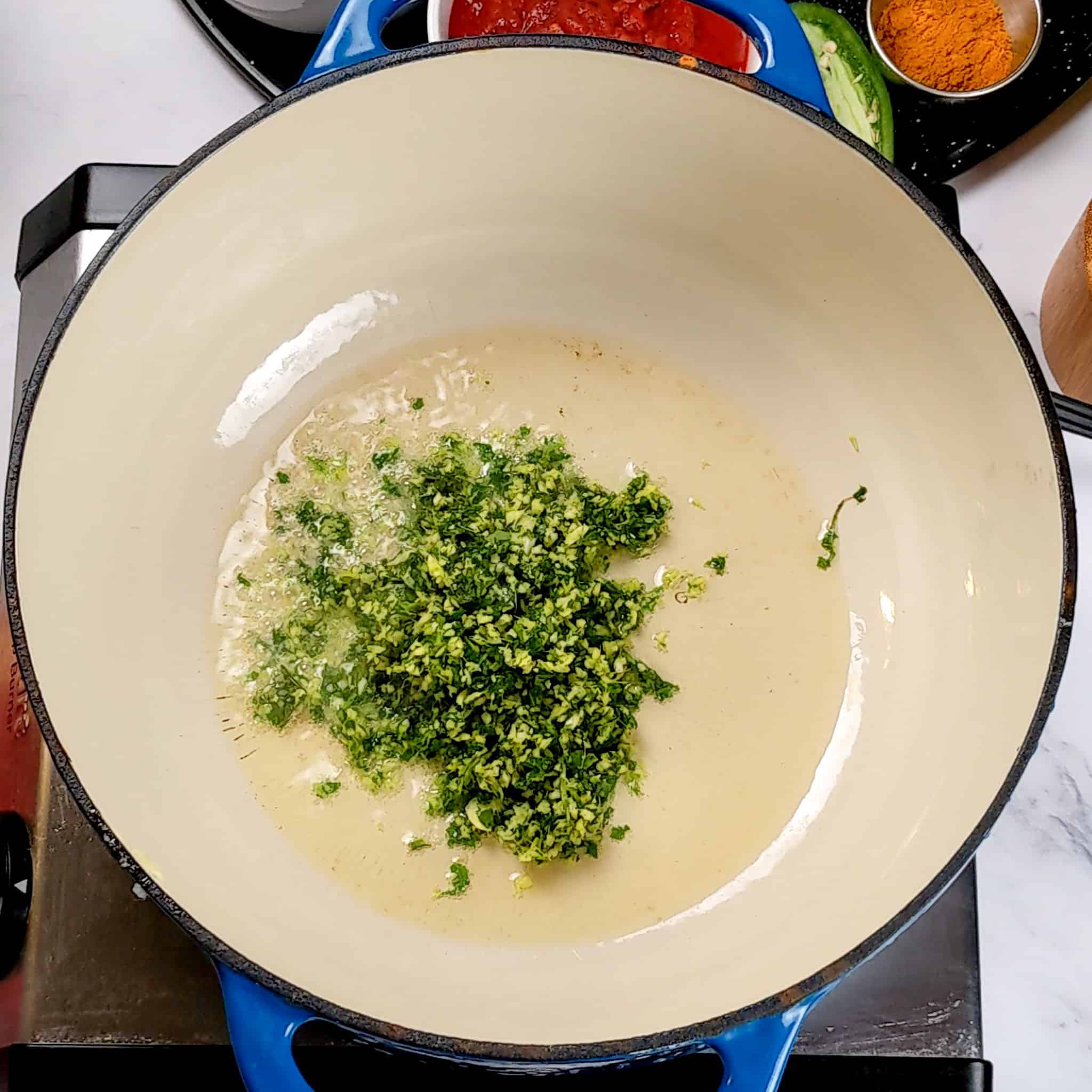 The blended aromatics of garlic, ginger and cilantro frying in oil and ghee in an lodge enameled Dutch oven for the Air Fryer Roasted Chicken Chickpeas Vegetable Curry recipe.