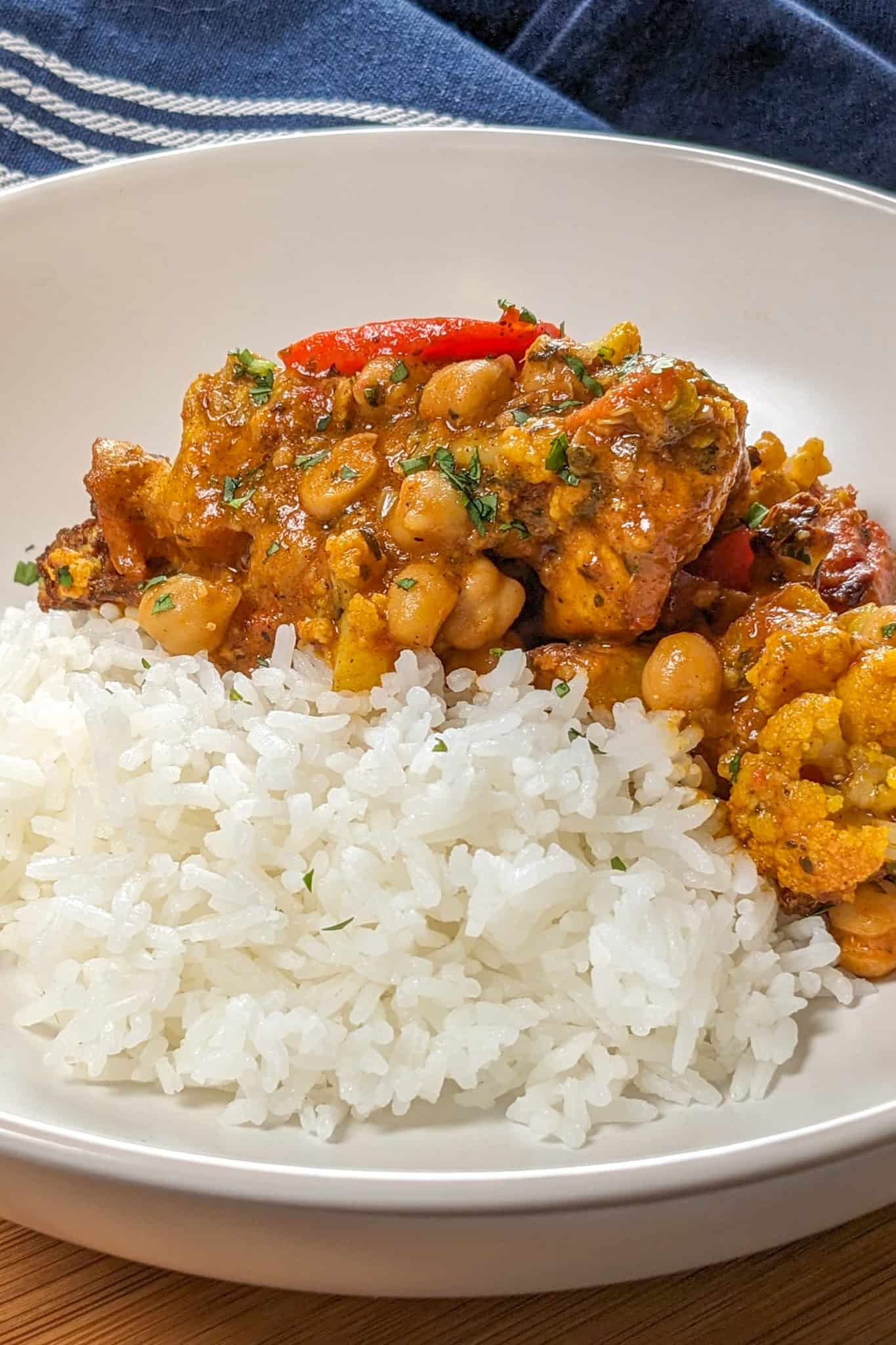 side view of the Air Fryer Roasted Chicken Chickpeas Vegetable Curry recipe in a wide rim bowl with basmati rice.