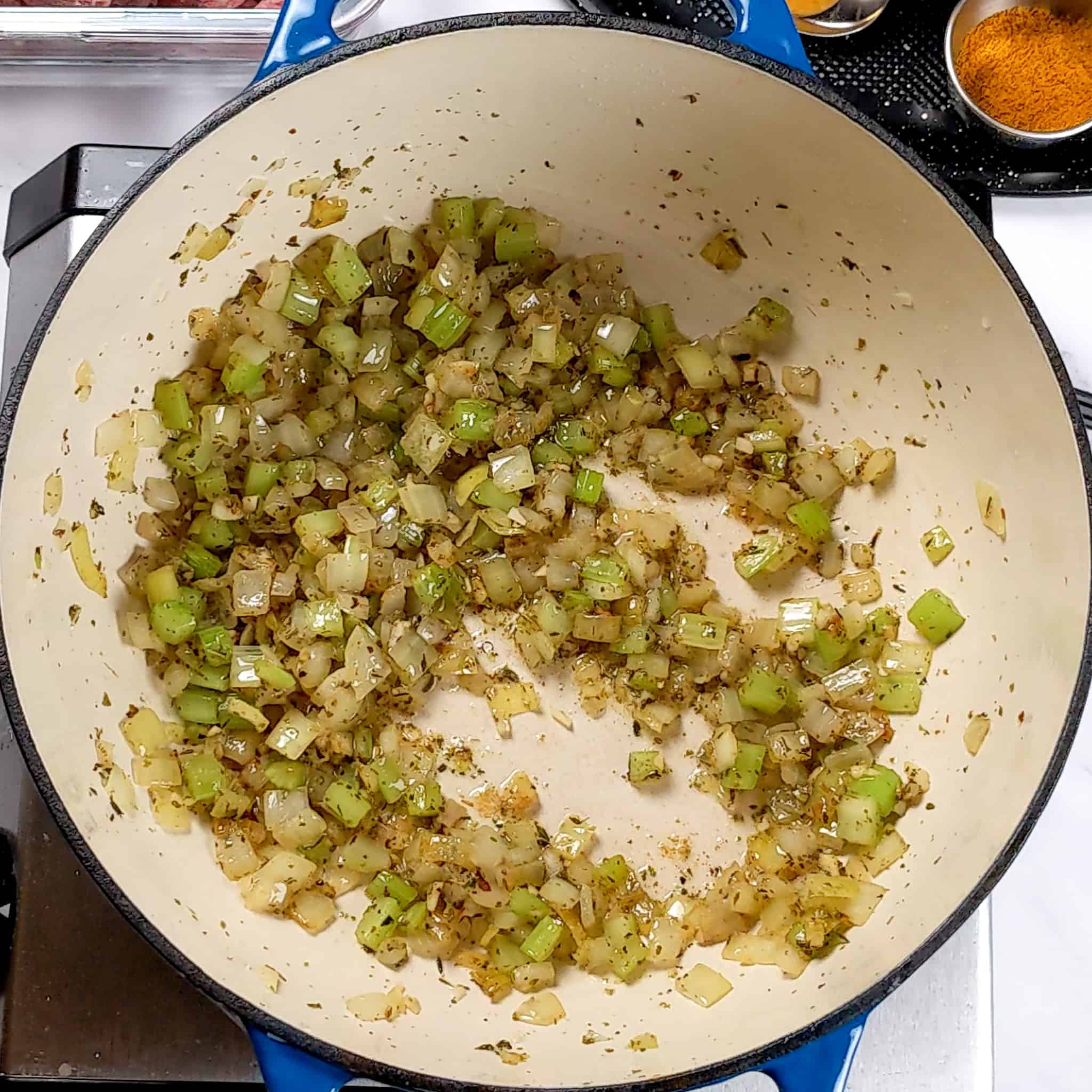 diced onion and celery, chopped garlic with dried thyme cooking in a a enameled dutch cooked down to where the onions are translucent and caramelized