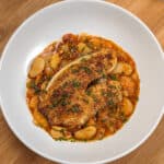 Top view of Pan-Seared Cajun Spiced Tilapia on White Bean Stew recipe in a wide rim bowl.