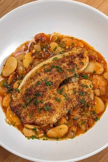 Top view of Pan-Seared Cajun Spiced Tilapia on White Bean Stew recipe in a wide rim bowl.
