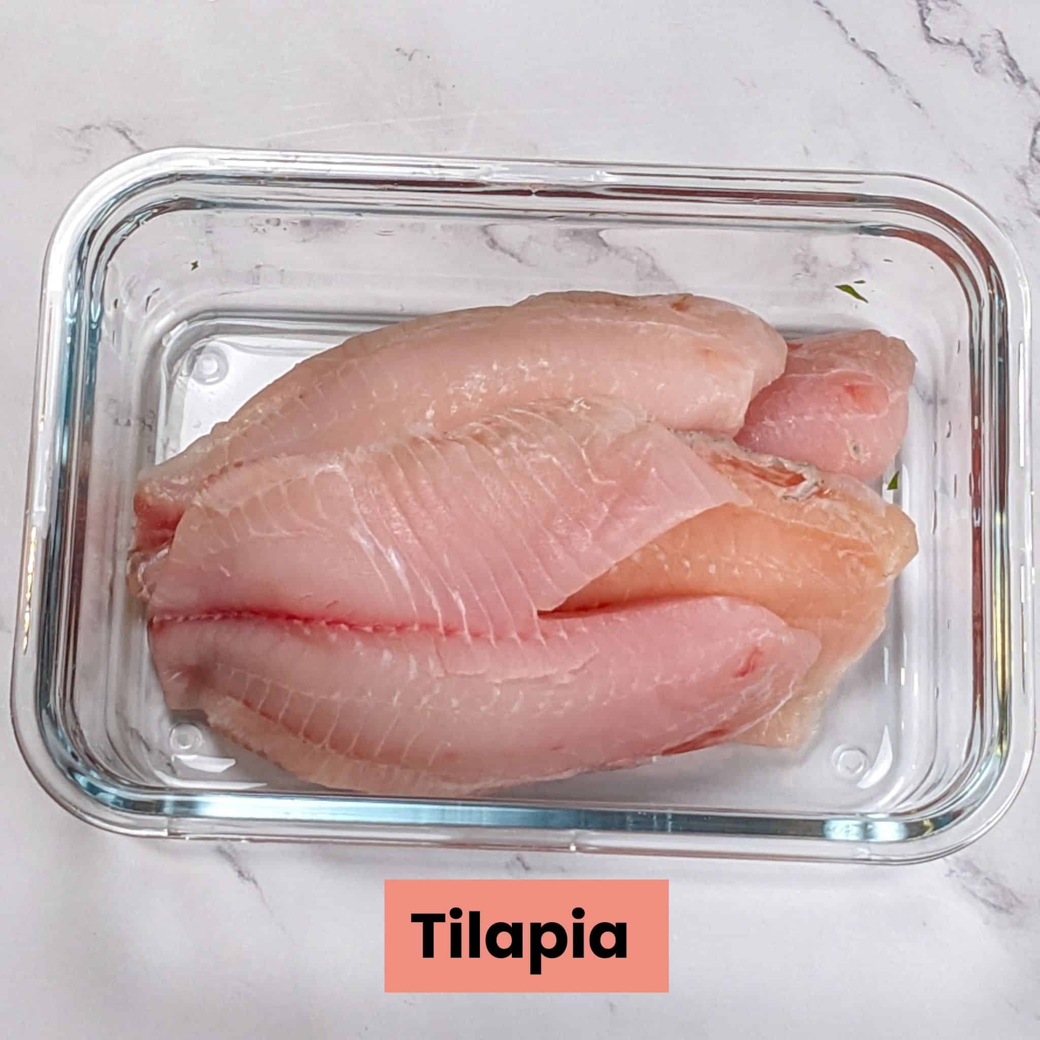 a pile of tilapia filets in a rectangle glass pan.