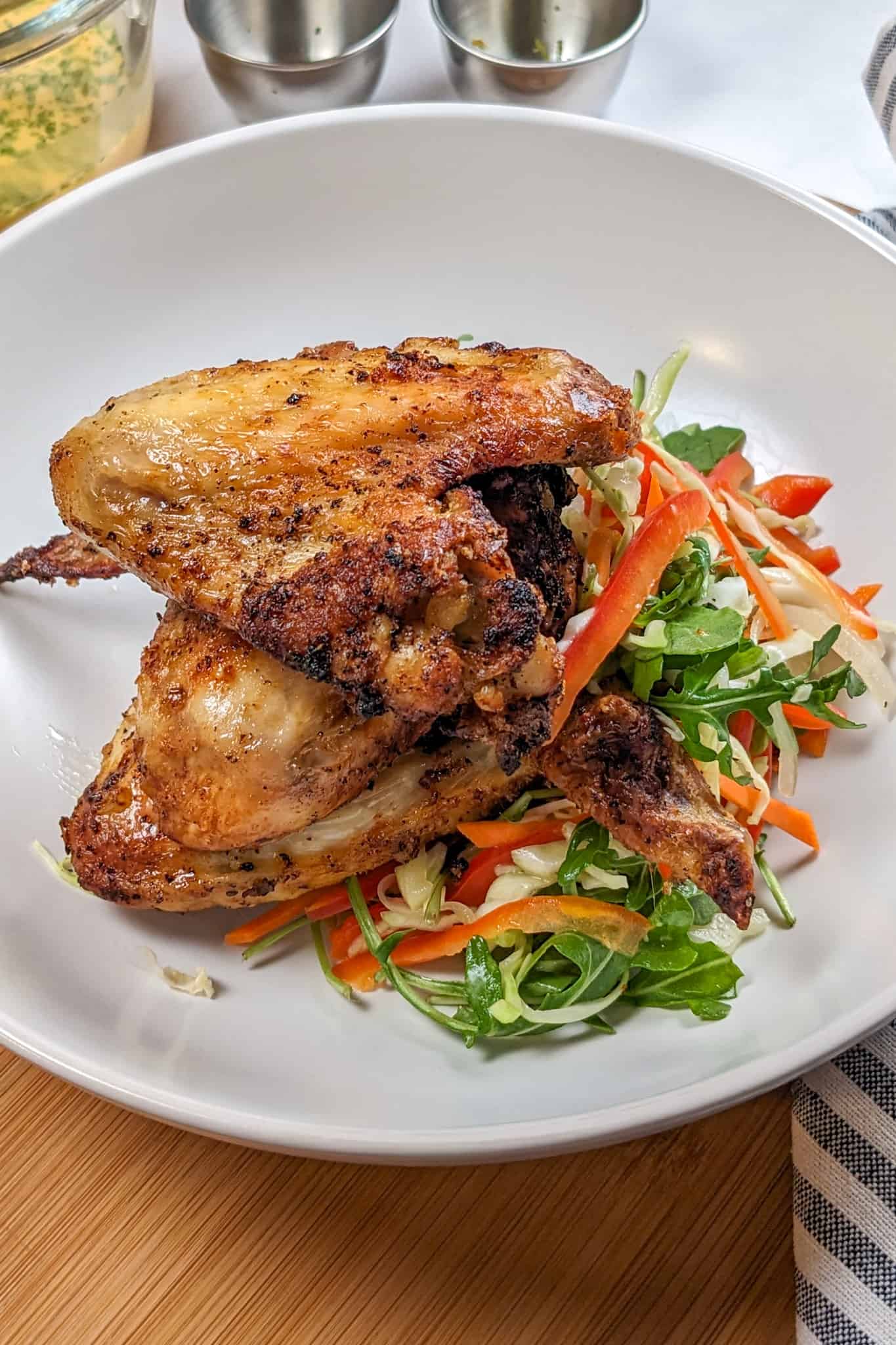 top view of the Best Air Fryer Caribbean Style Citrus Chicken Wings next to a salad mix on a wide rim bowl