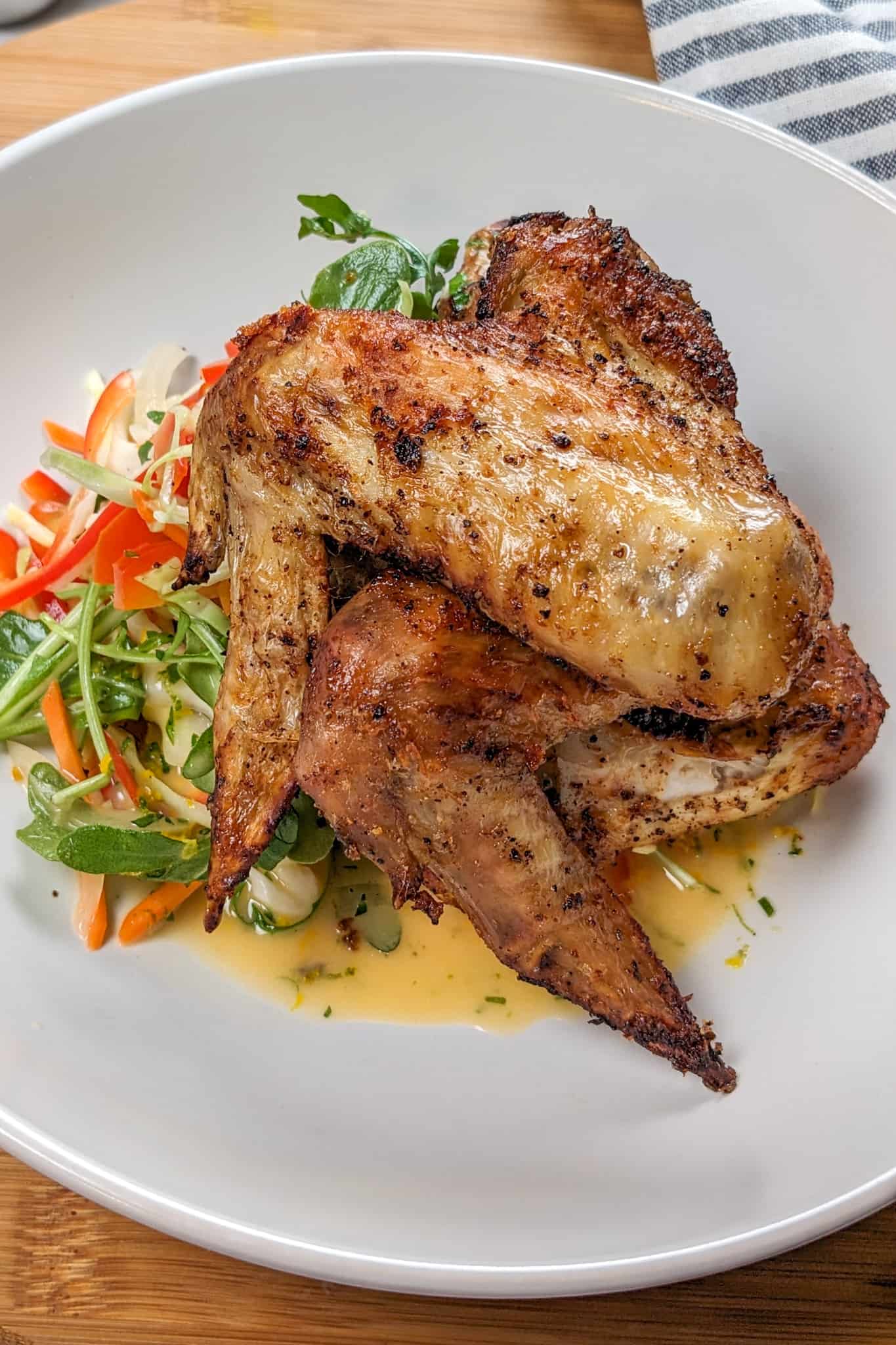 side view of the Best Air Fryer Caribbean Style Citrus Chicken Wings recipe in wide rim bowl with salad and vinaigrette