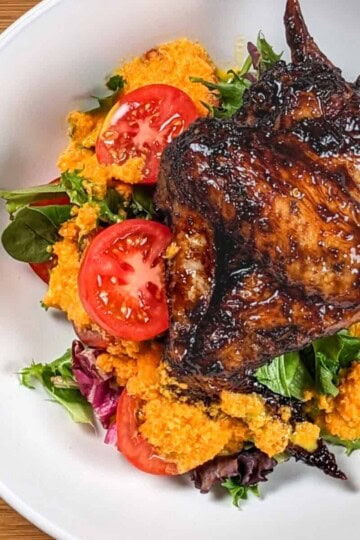 top view of the Easy Air Fryer Sticky Date Teriyaki Chicken Wings next to a salad of mixed greens sliced campari tomatoes with carrot ginger dressing in a wide rim bowl