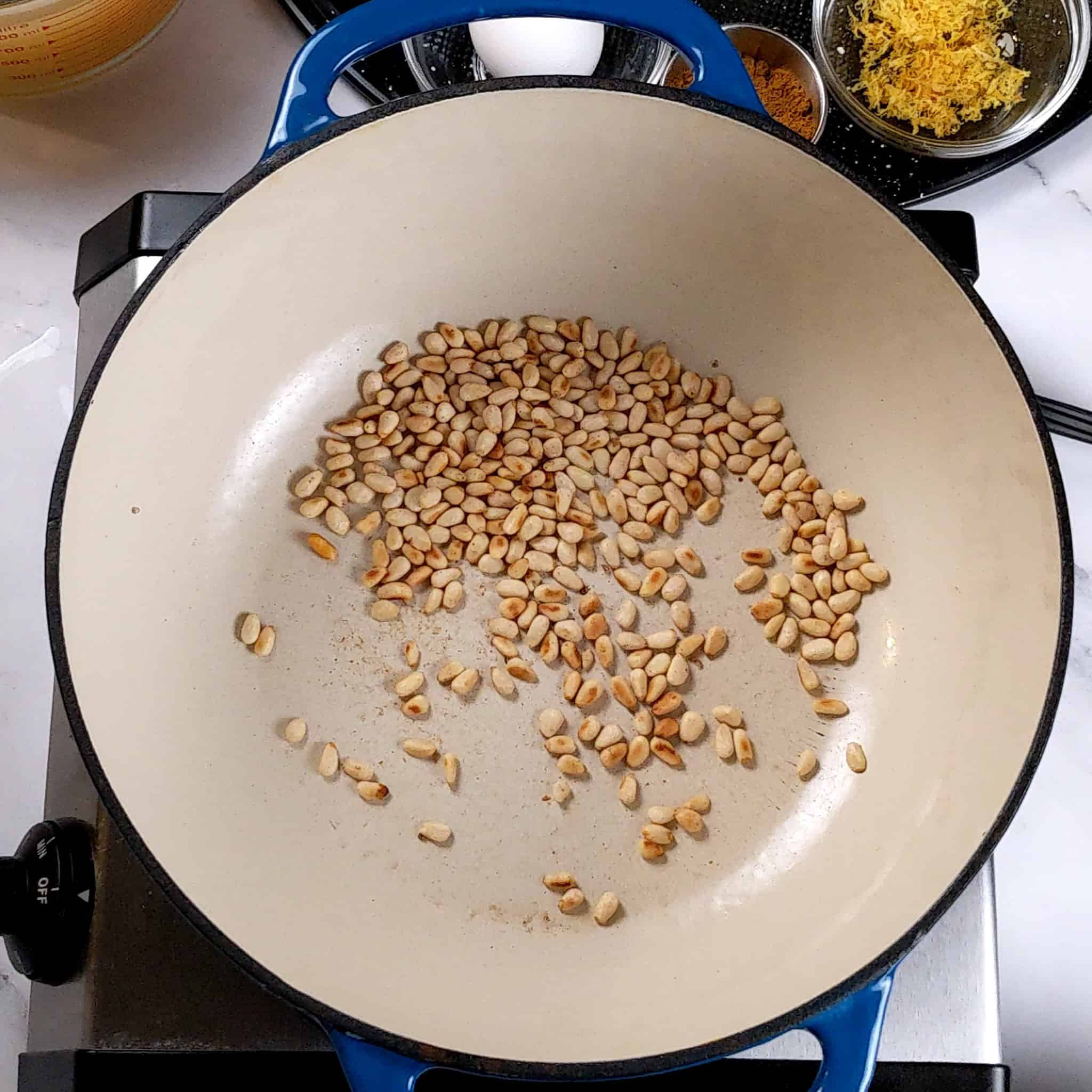 pine nuts toasting in an enameled dutch oven