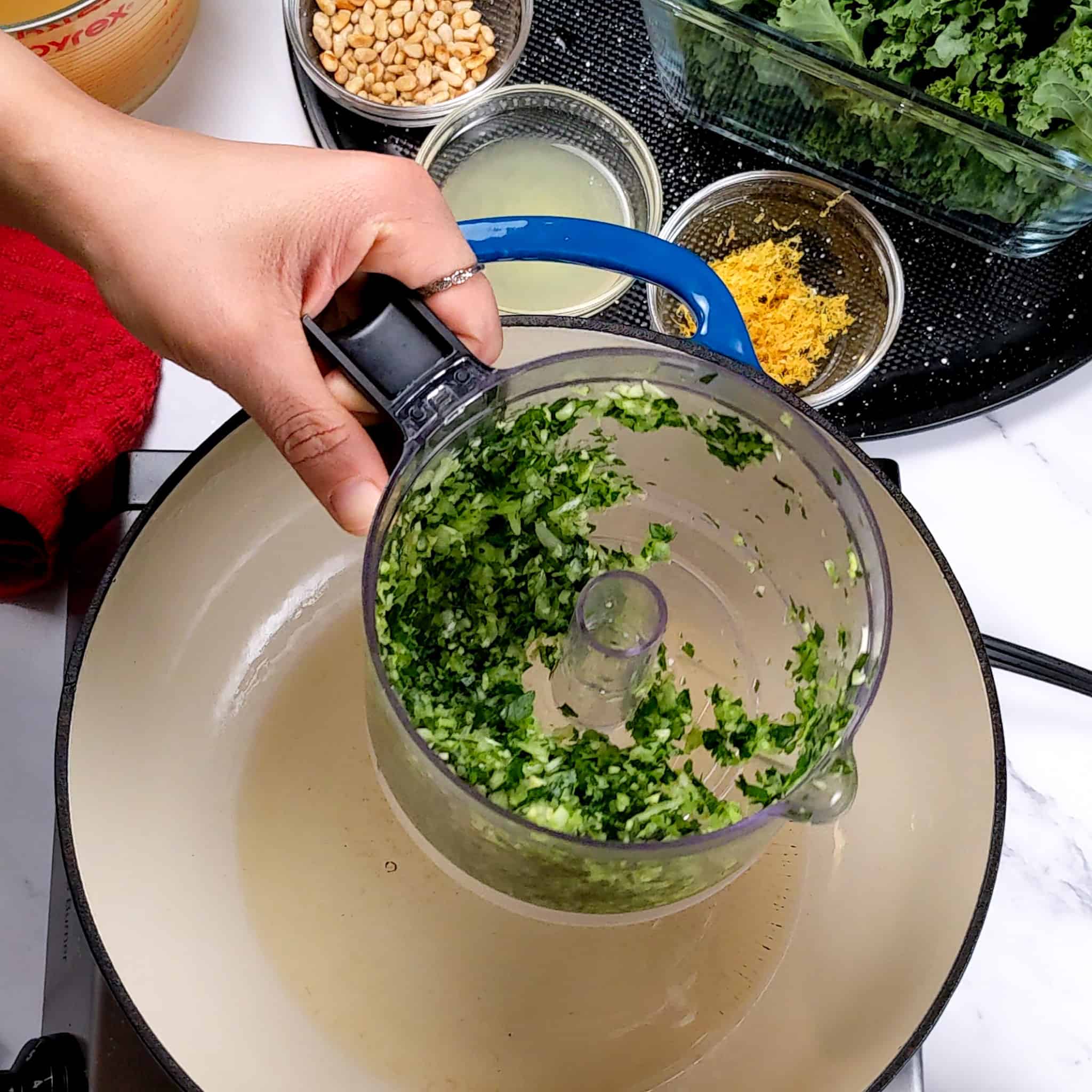 blended aromatics in a food processor over an enameled dutch oven surrounded by other Easy and Healthy Spicy Turkey Meatball Kale Soup ingredients