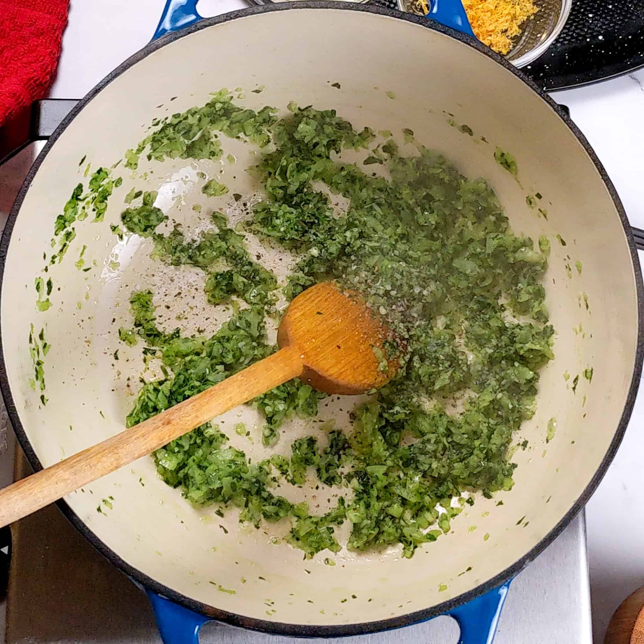 the blended aromatics sweating in the enameled dutch oven with a wooden spoon resting inside